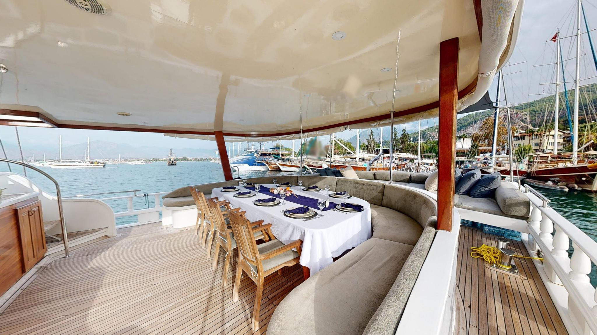 yacht aft deck with curved banquette seating, formal dining table and marina views