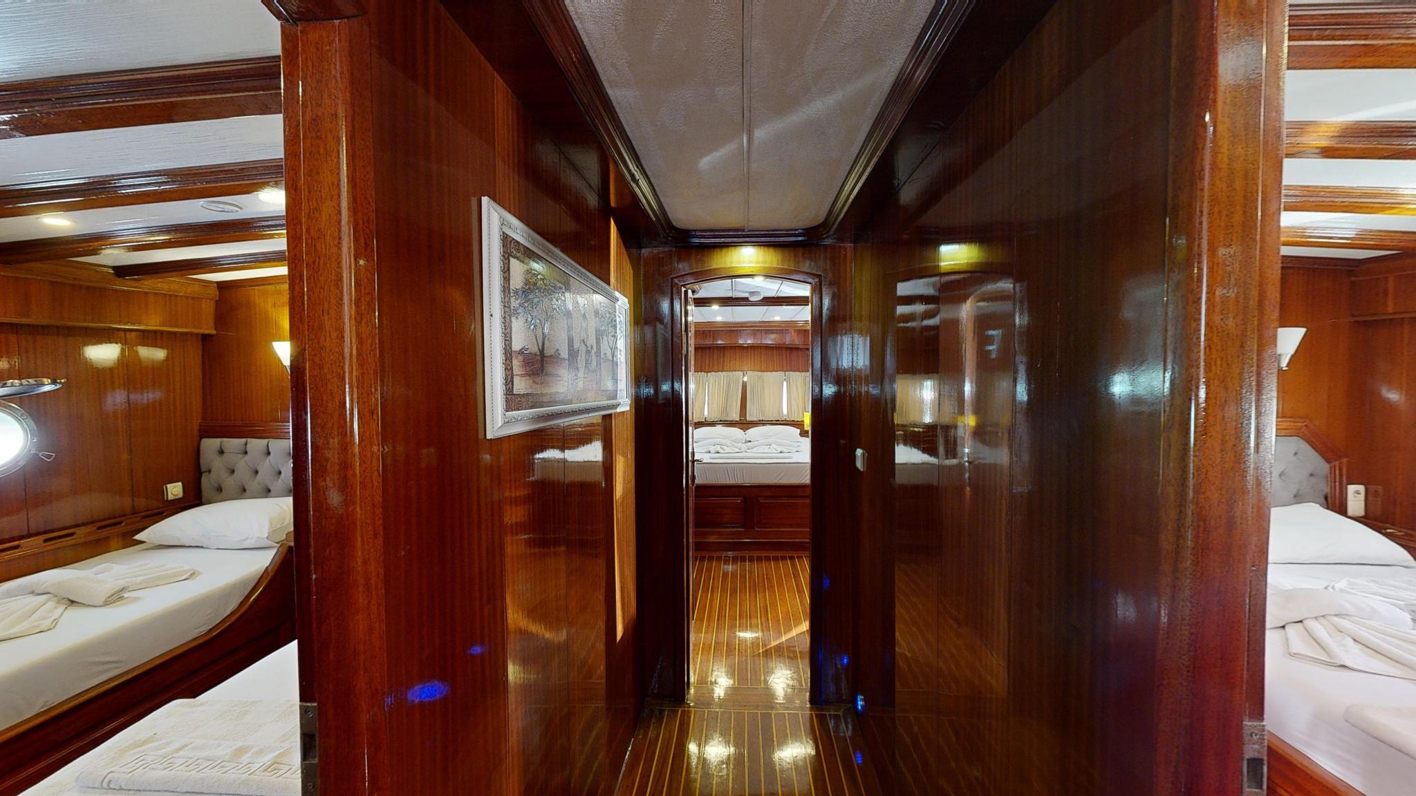 yacht interior corridor showing guest cabins with twin beds and mahogany woodwork