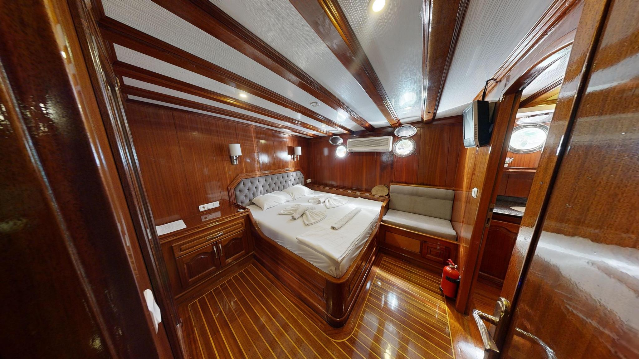 yacht guest cabin featuring double bed with gray tufted headboard and white linens