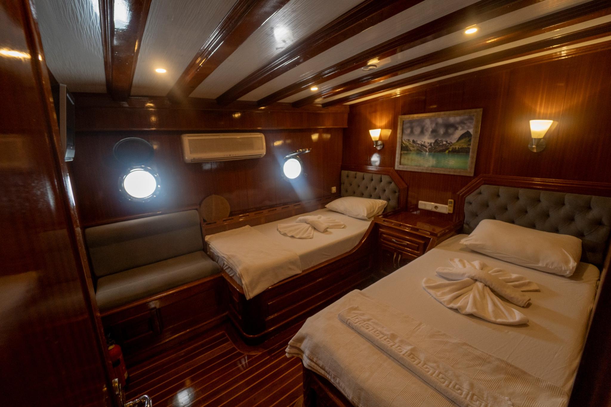 yacht twin cabin with two single beds, upholstered headboards and round portholes