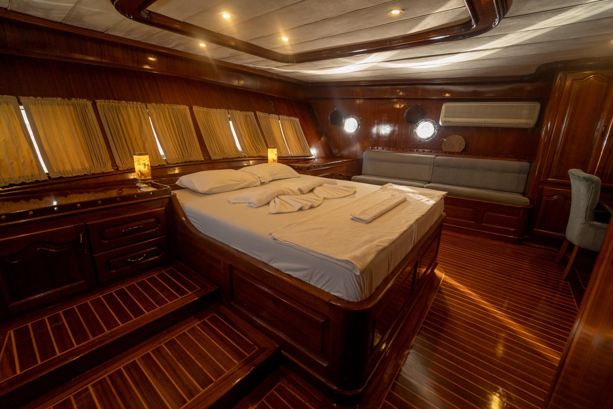 luxury yacht master cabin featuring double bed with white linens and two circular portholes