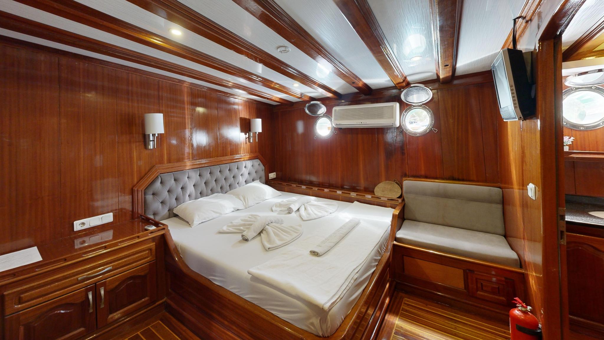 yacht guest cabin featuring double bed with tufted headboard and built-in seating bench
