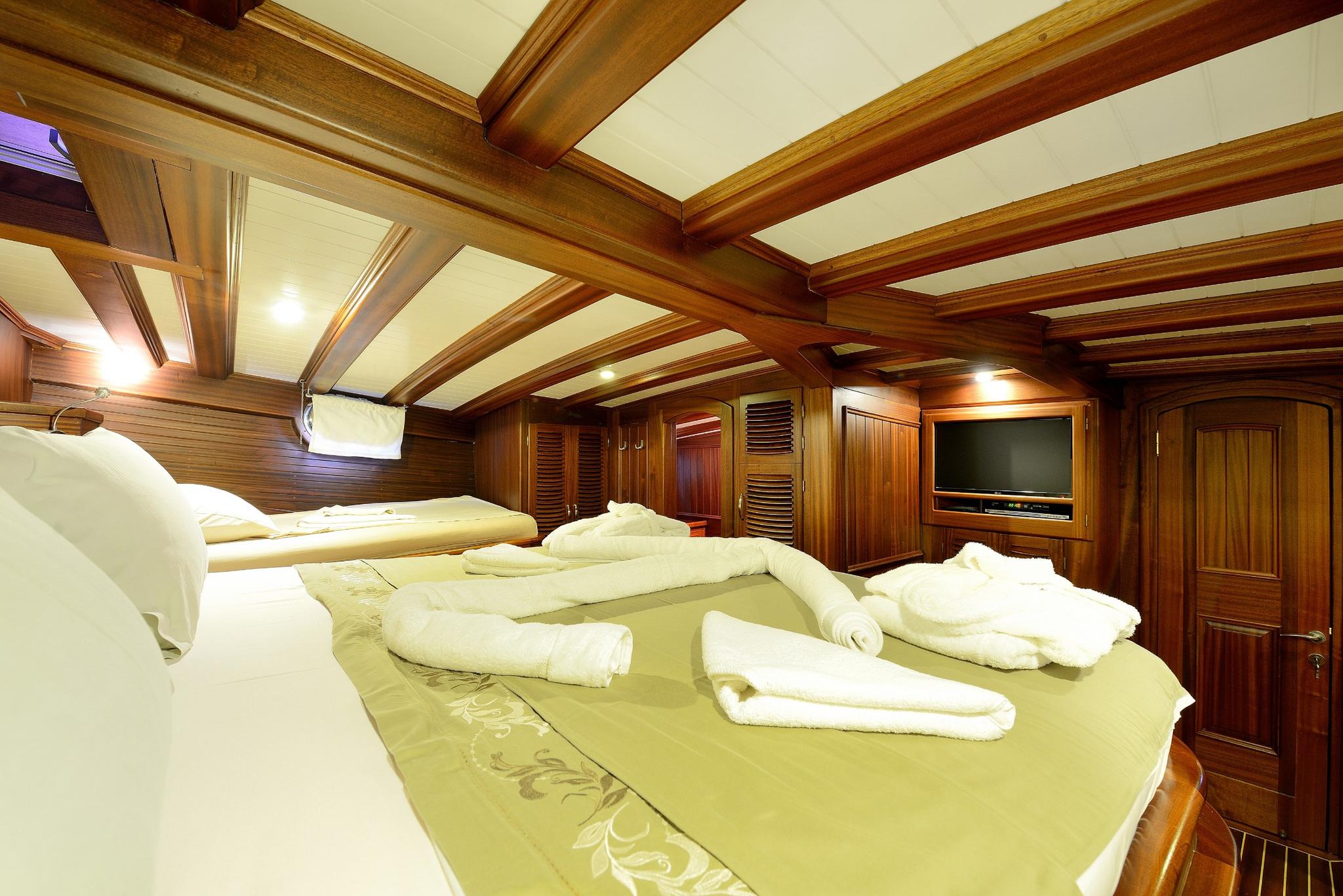 yacht guest cabin with twin beds, wooden paneling, built-in TV and storage