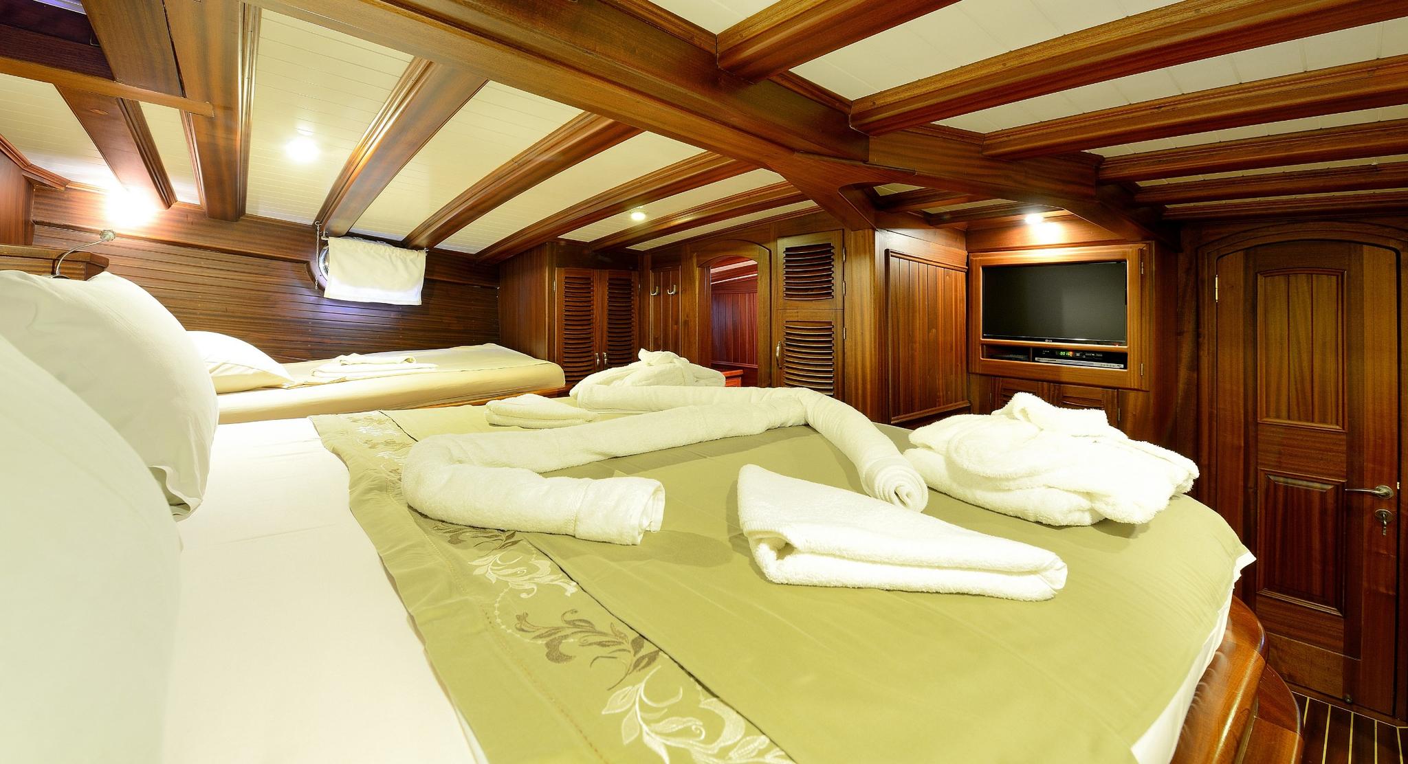 yacht guest cabin featuring twin beds with yellow bedding and white towels arranged