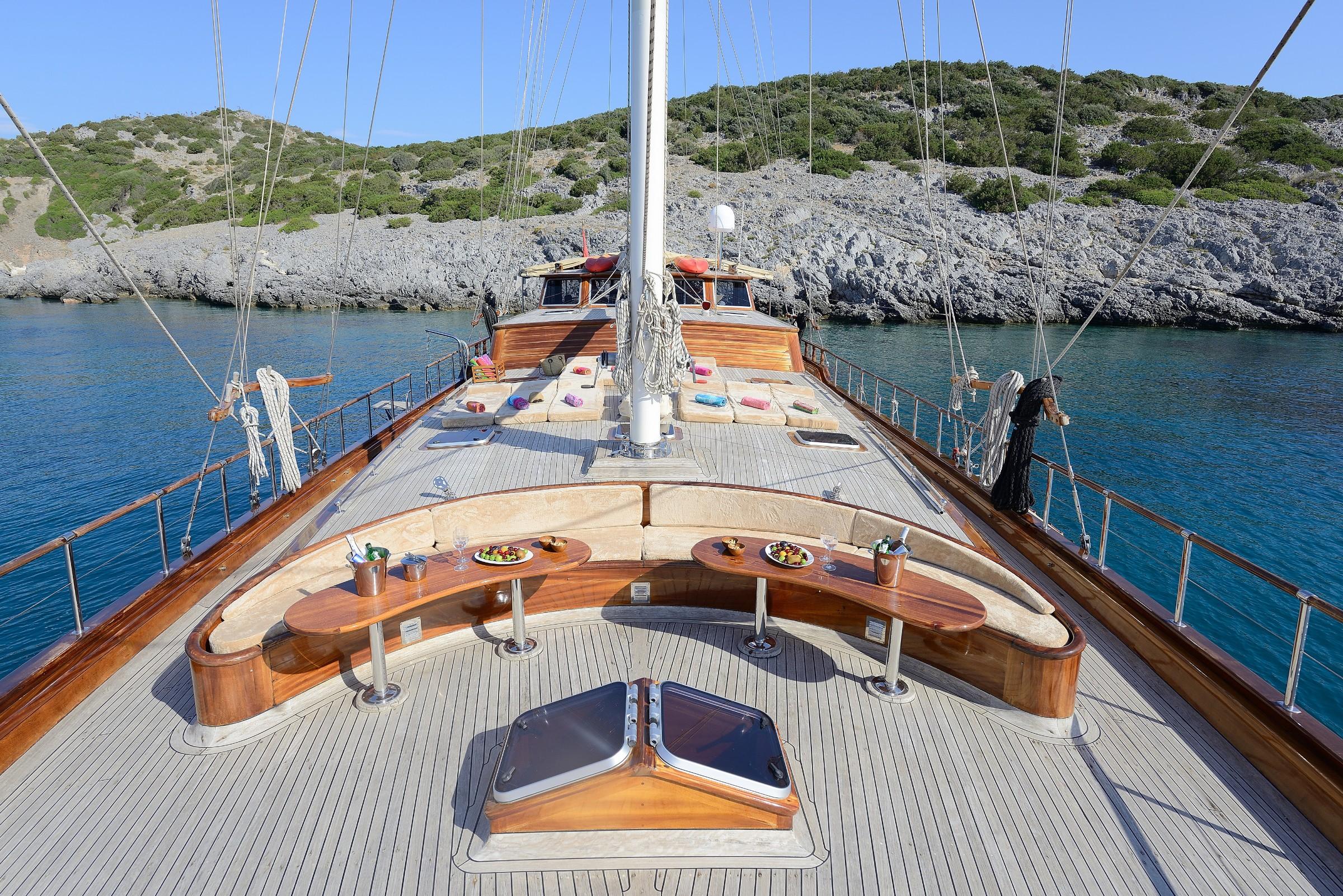 gulet bow deck with curved wooden dining table, bench seating and champagne service