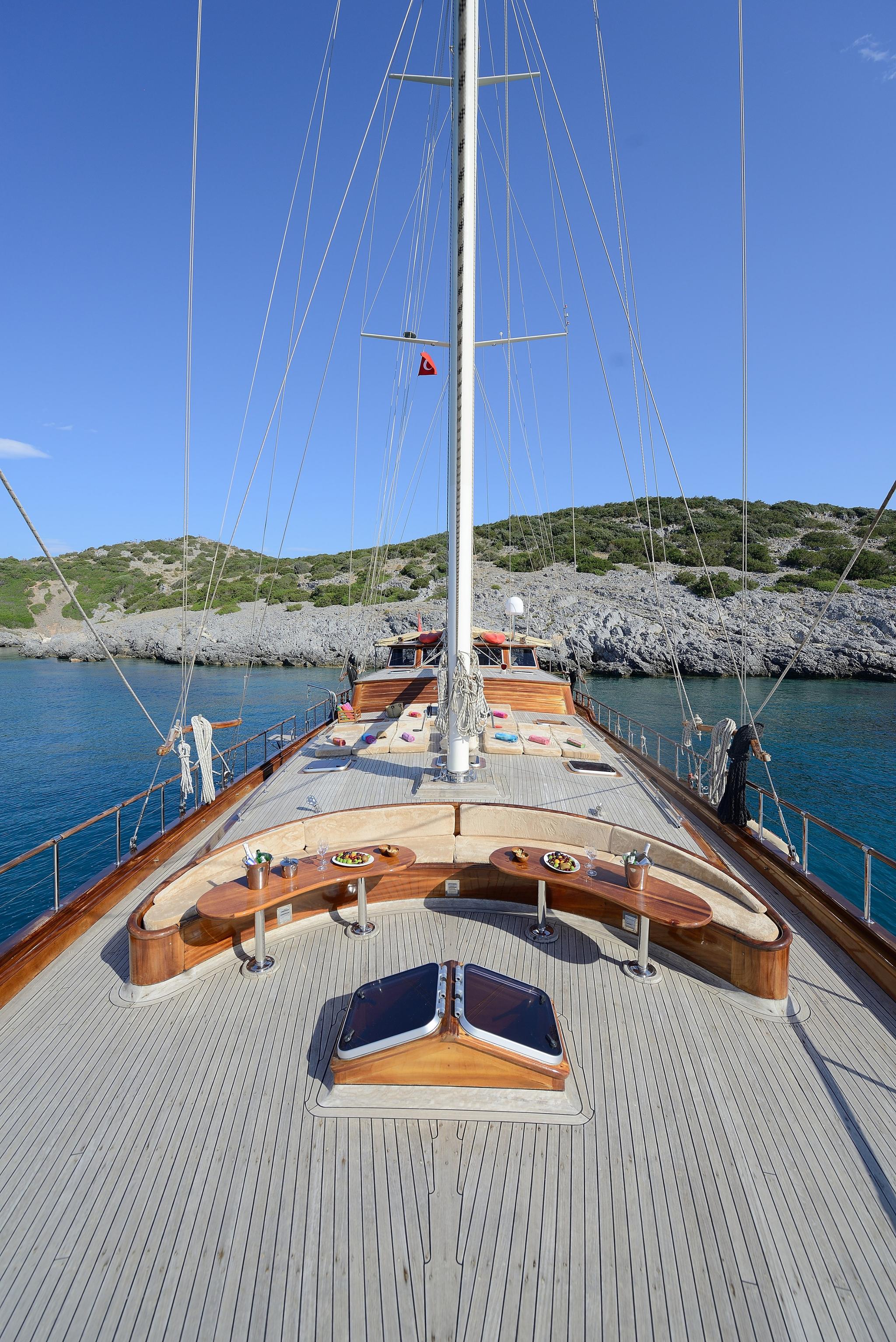 gulet forward deck featuring curved teak dining table with place settings and central mainmast