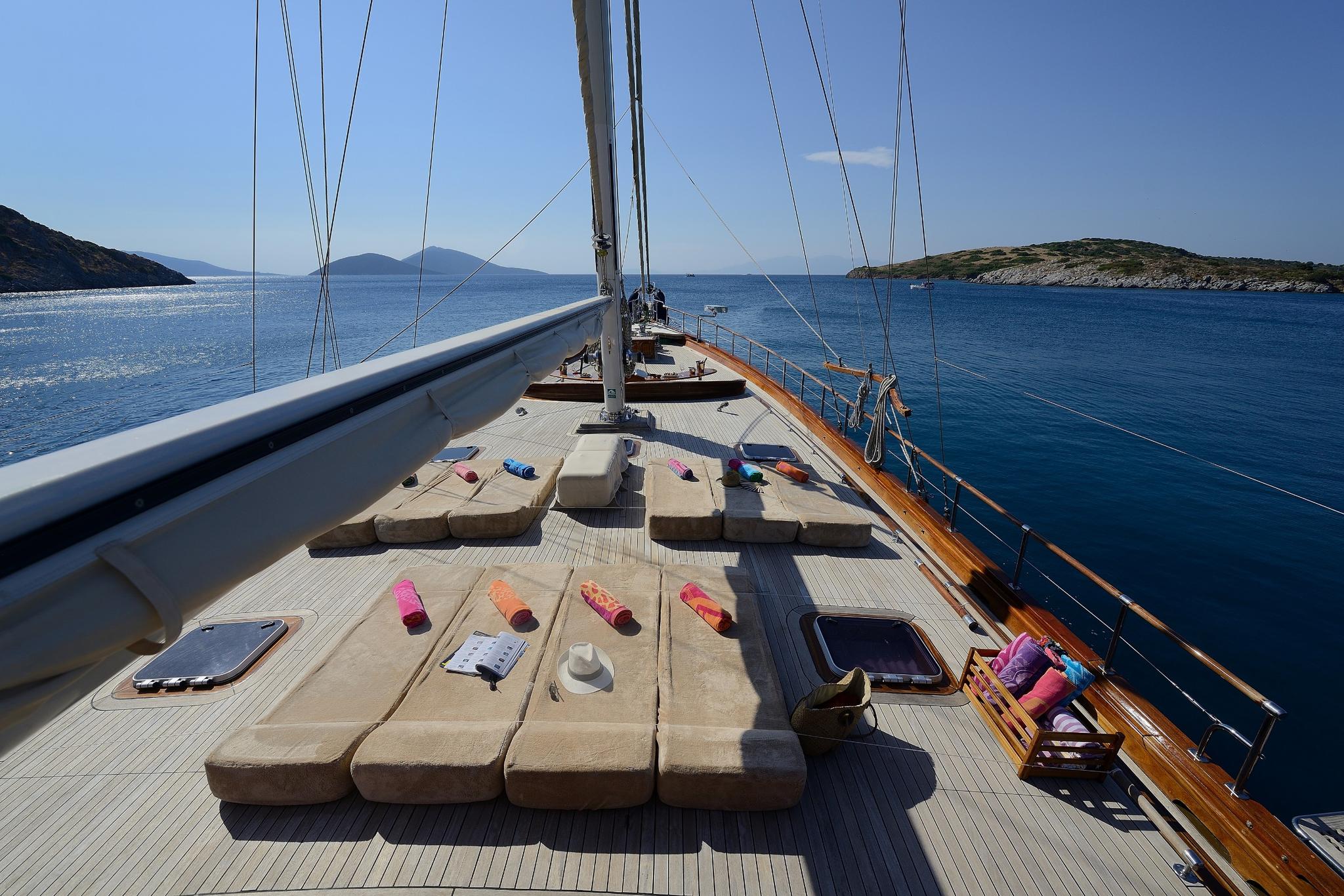 gulet bow deck with large cream sunbathing cushions and sailing rigging