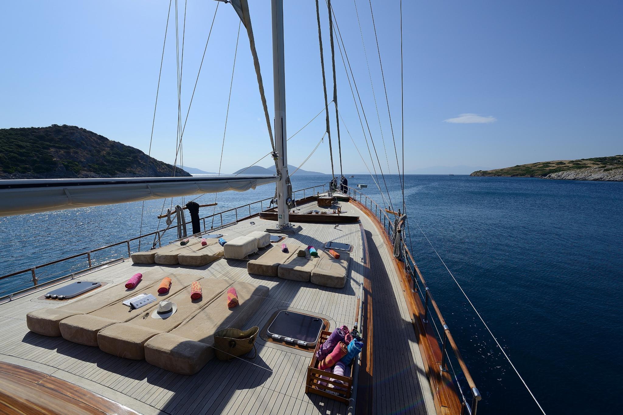 gulet forward deck with beige cushioned seating area around central sailing mast