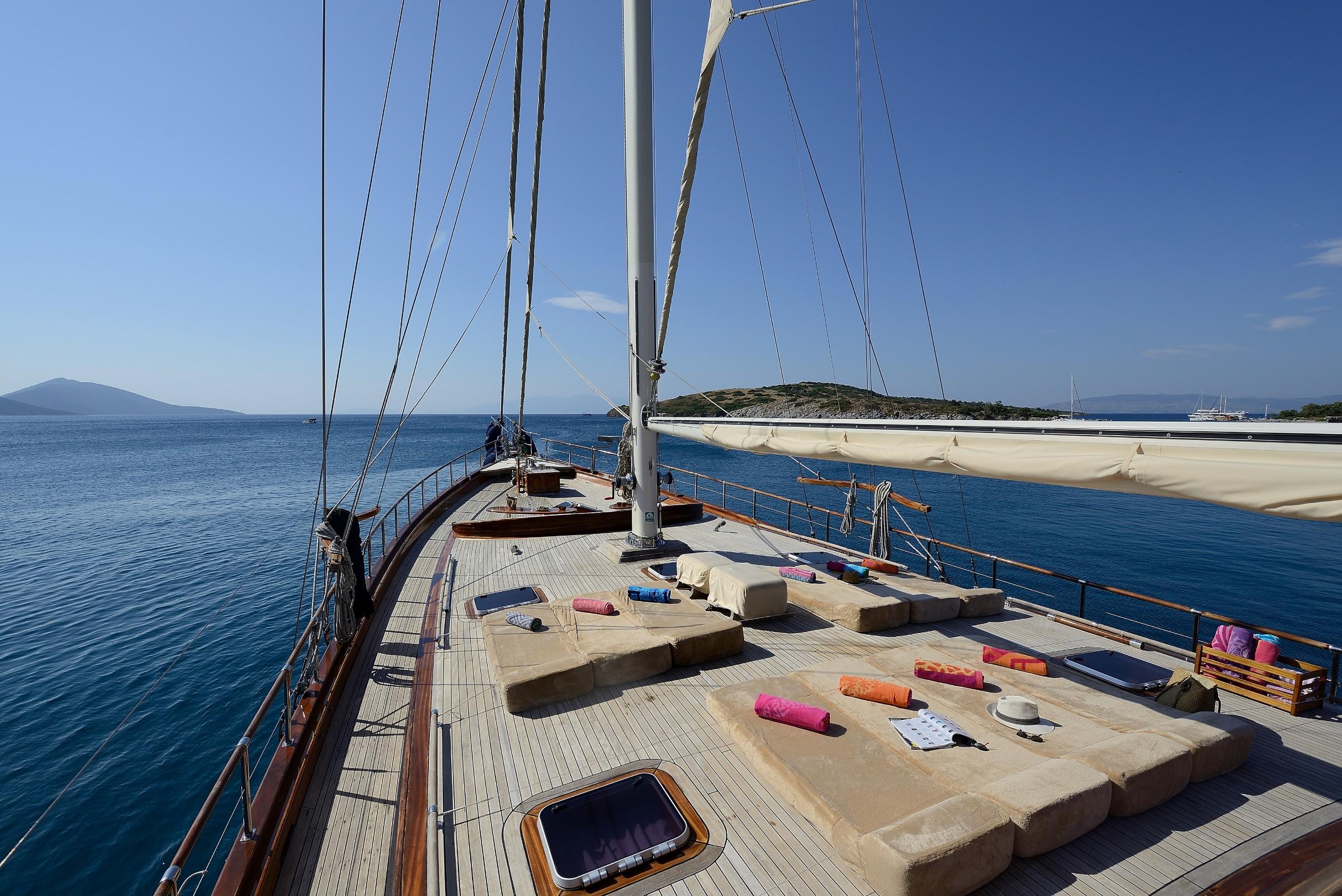 gulet forward deck with built-in cushioned seating area around central mast at sea