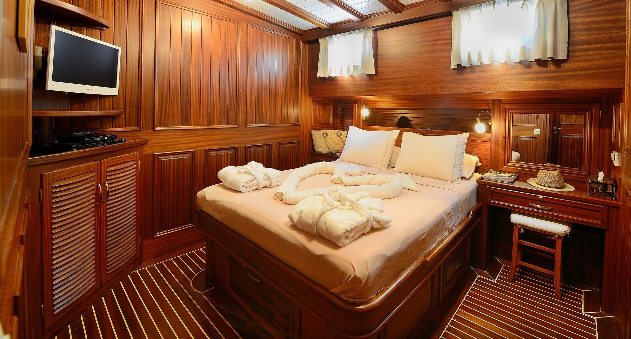luxury yacht master cabin with double bed, flat screen TV, wood paneling and skylights