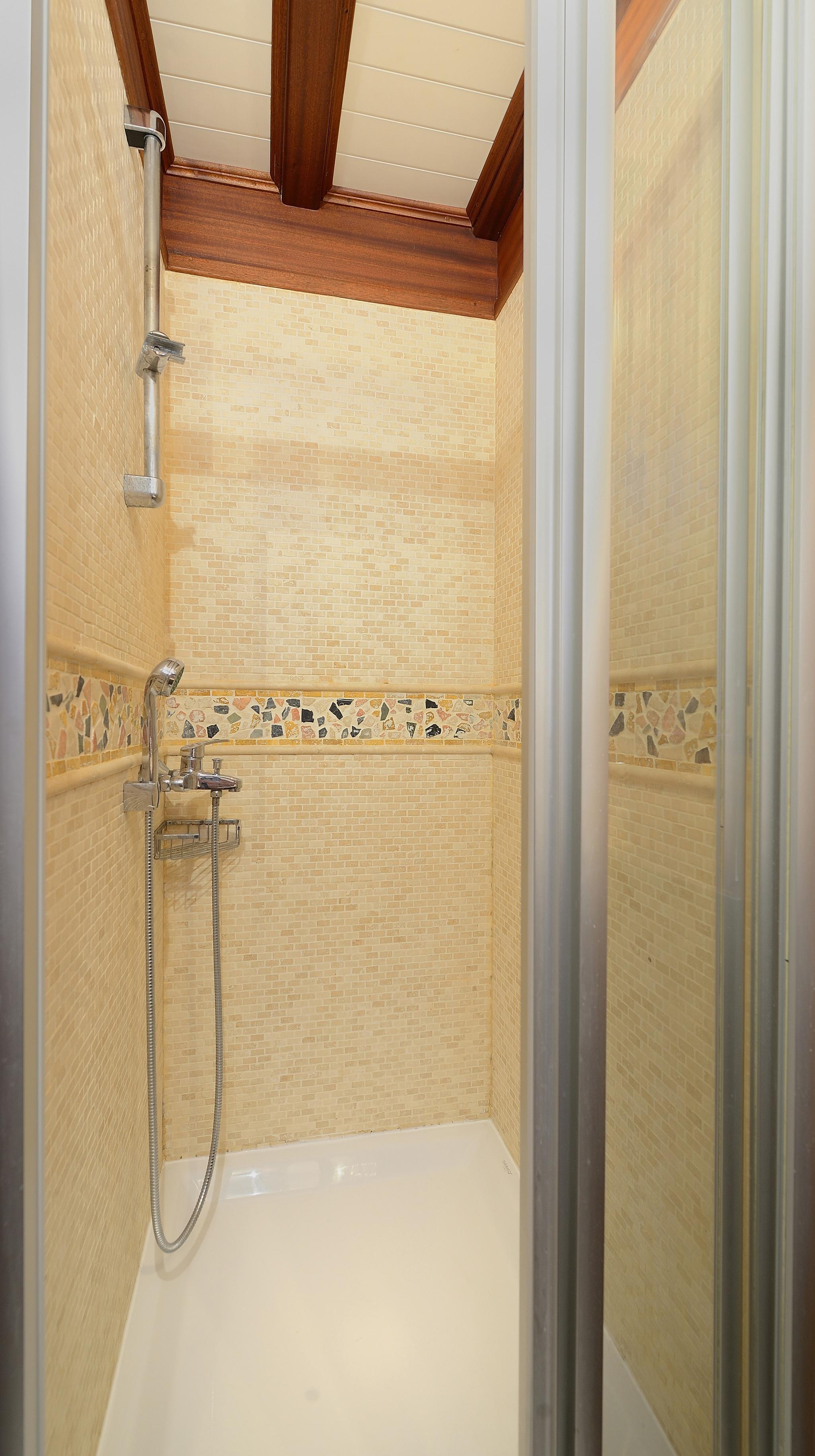 yacht shower stall with cream mosaic tiles and decorative stone border accent