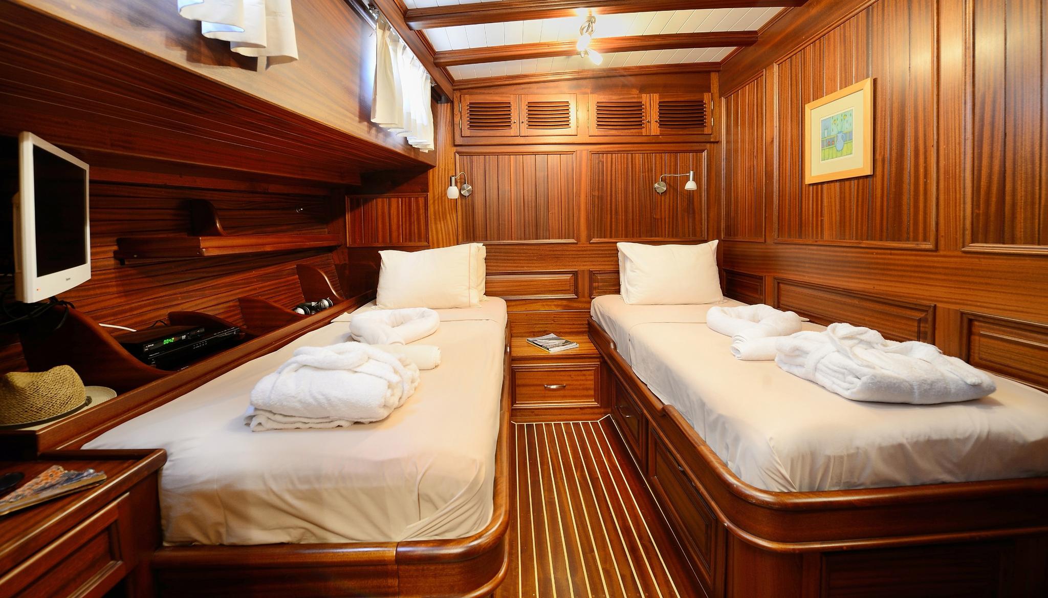 Twin guest cabin with two single beds, rich wood paneling and entertainment system