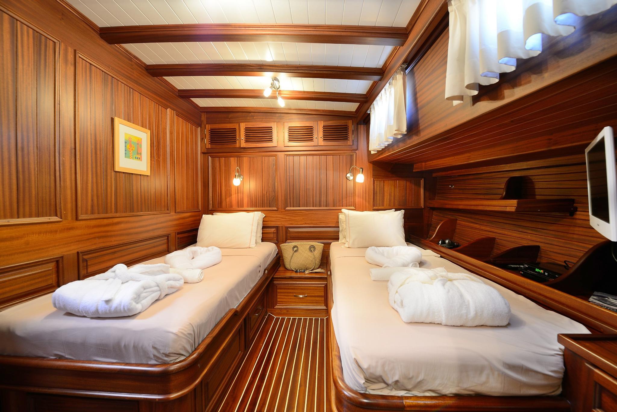 twin cabin interior with two single beds, rich wood paneling and white linens