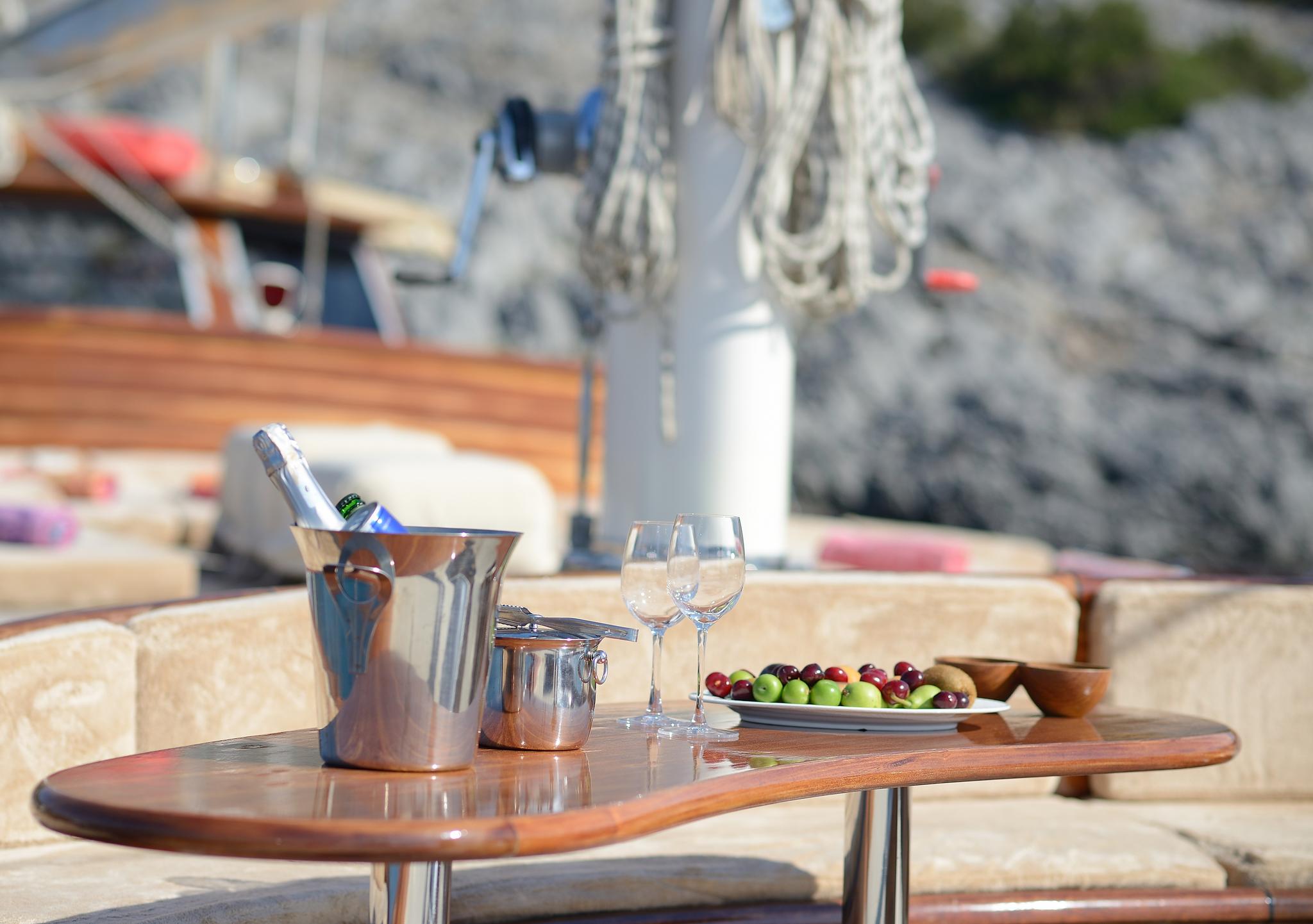champagne bucket with wine glasses and fresh fruit platter served on yacht deck table