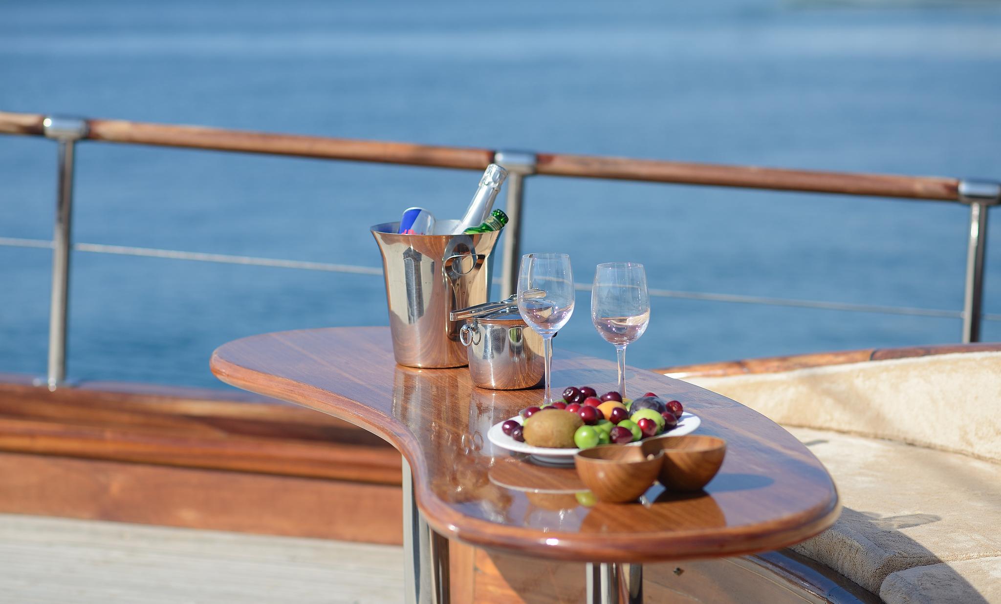 deck dining table with champagne bucket, wine glasses and fresh fruit platter overlooking ocean
