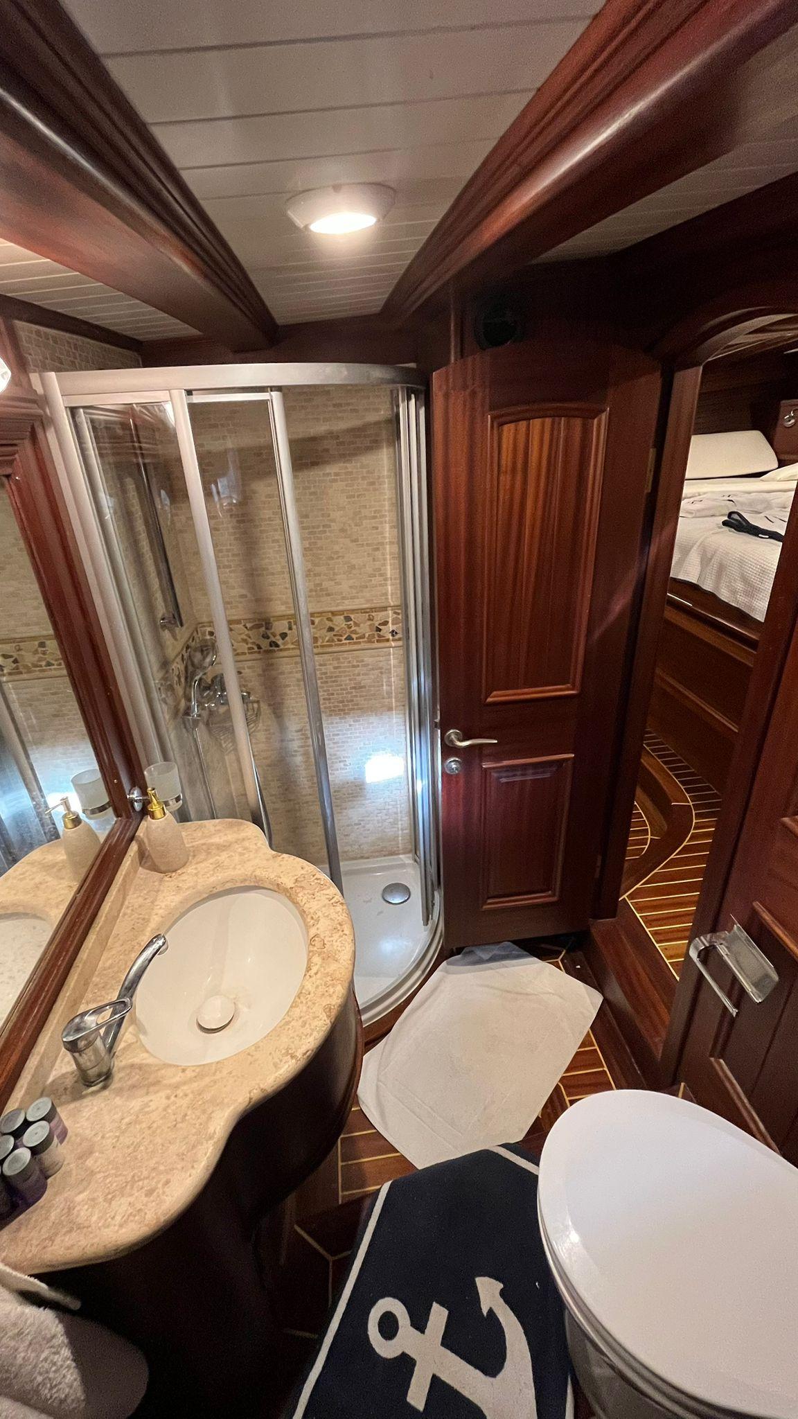 luxury yacht guest cabin ensuite bathroom featuring marble vanity, glass shower enclosure with mosaic tile walls
