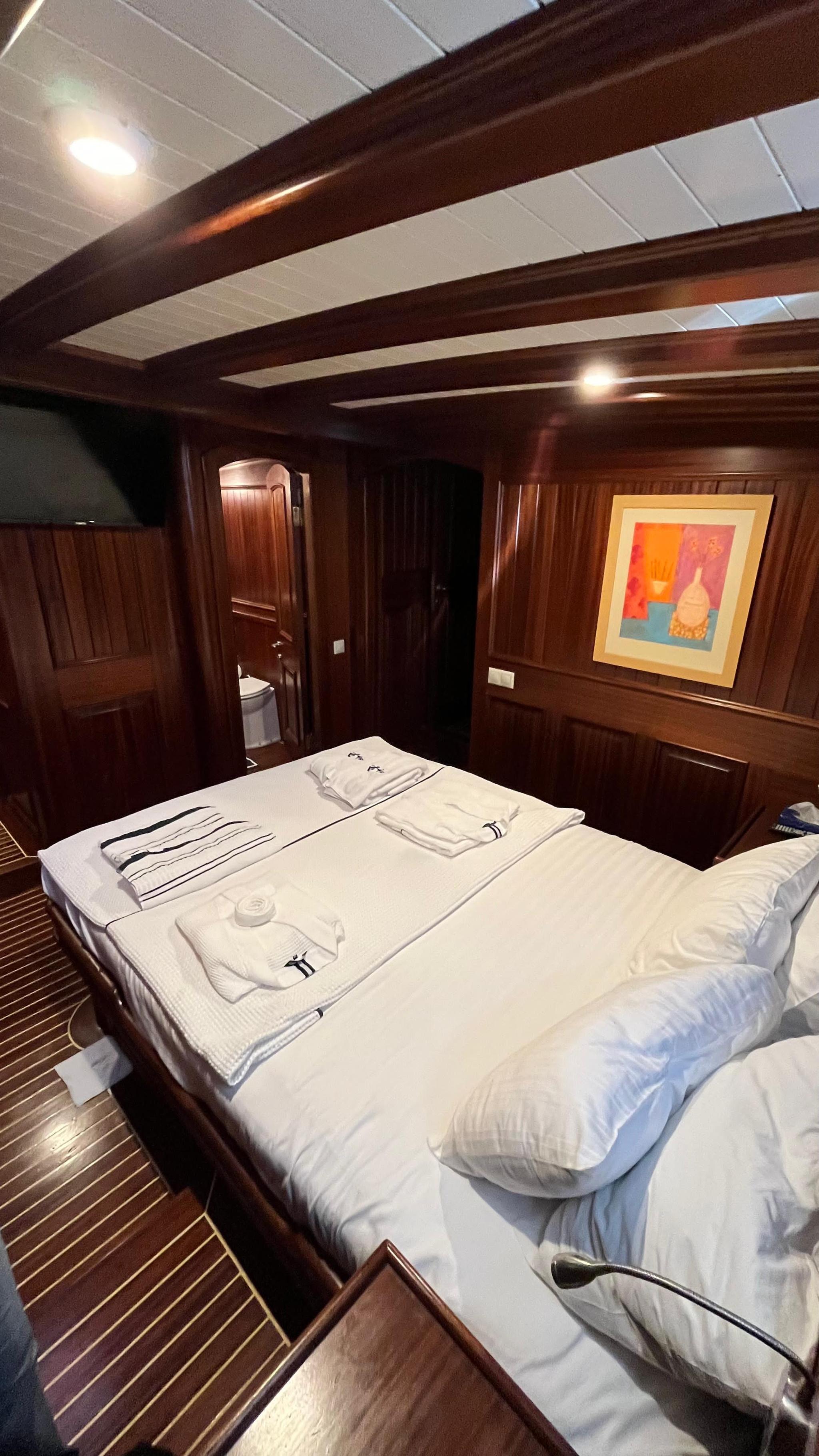 yacht guest cabin featuring double bed with white linens and en-suite bathroom door
