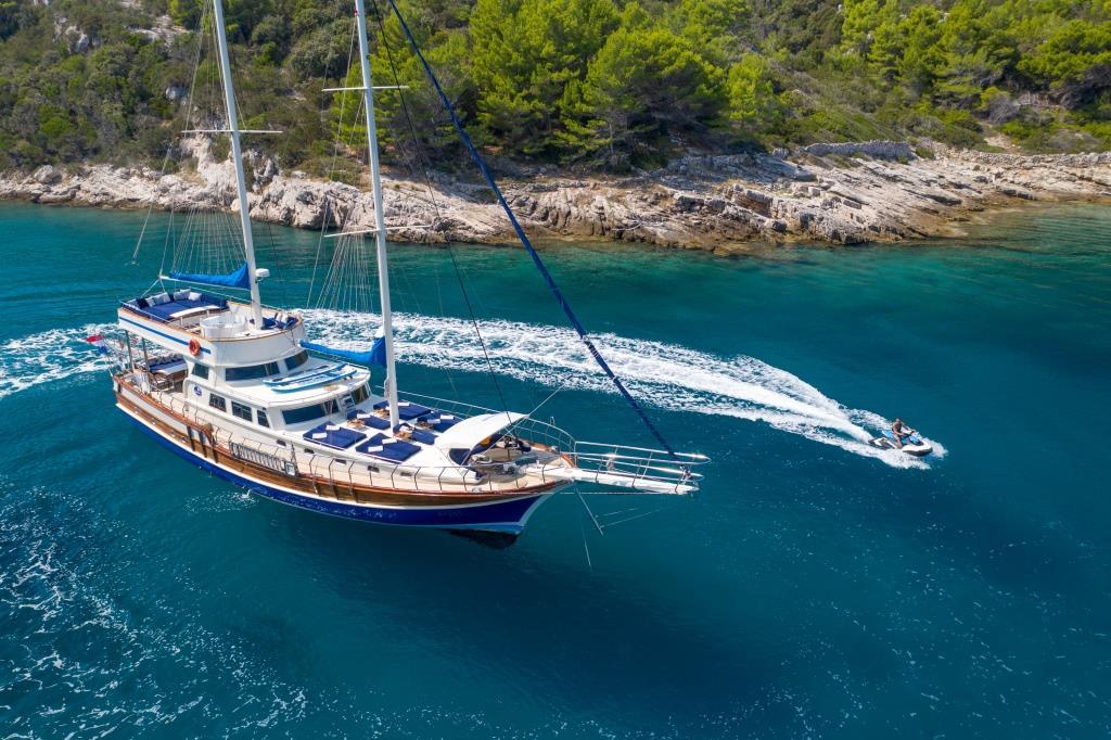 Aerial view of wooden gulet yacht with tender boat in Mediterranean bay