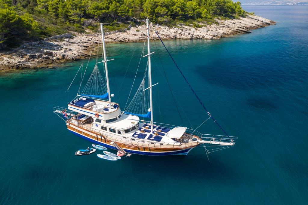 Aerial view of wooden gulet yacht anchored in crystal clear turquoise waters
