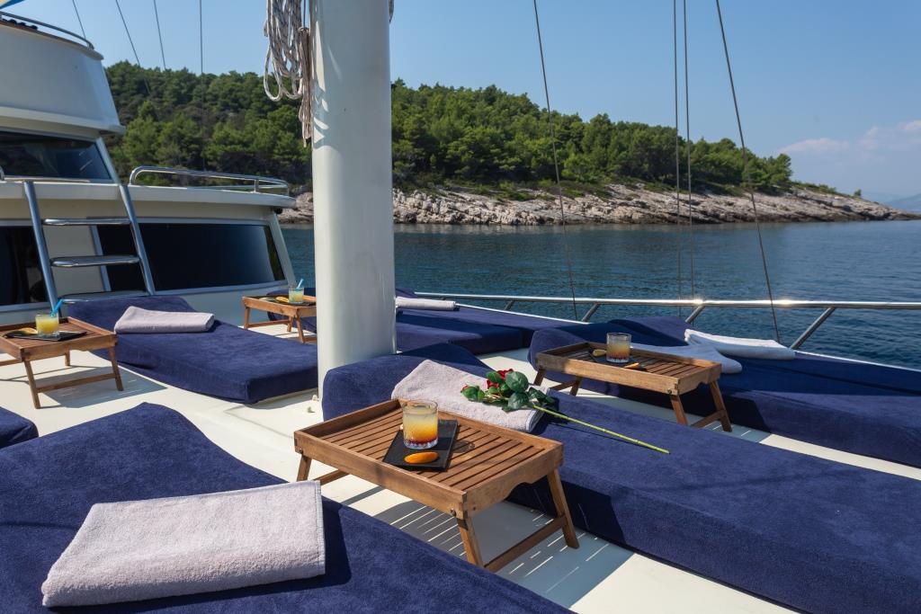yacht forward deck with blue cushioned seating areas around white mast