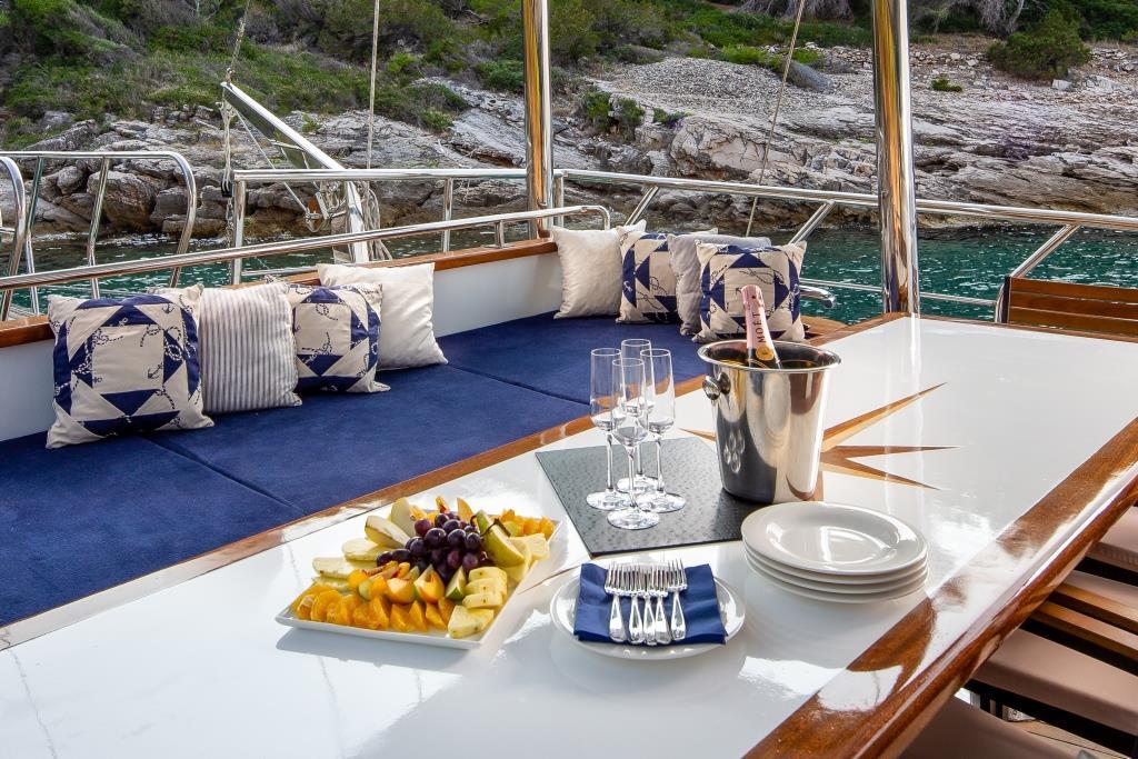 luxury yacht aft deck dining setup with champagne and fresh fruit platter