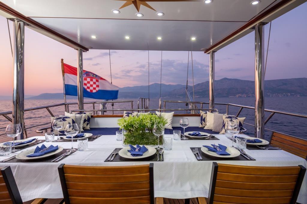 luxury yacht aft deck dining table set for dinner at sunset