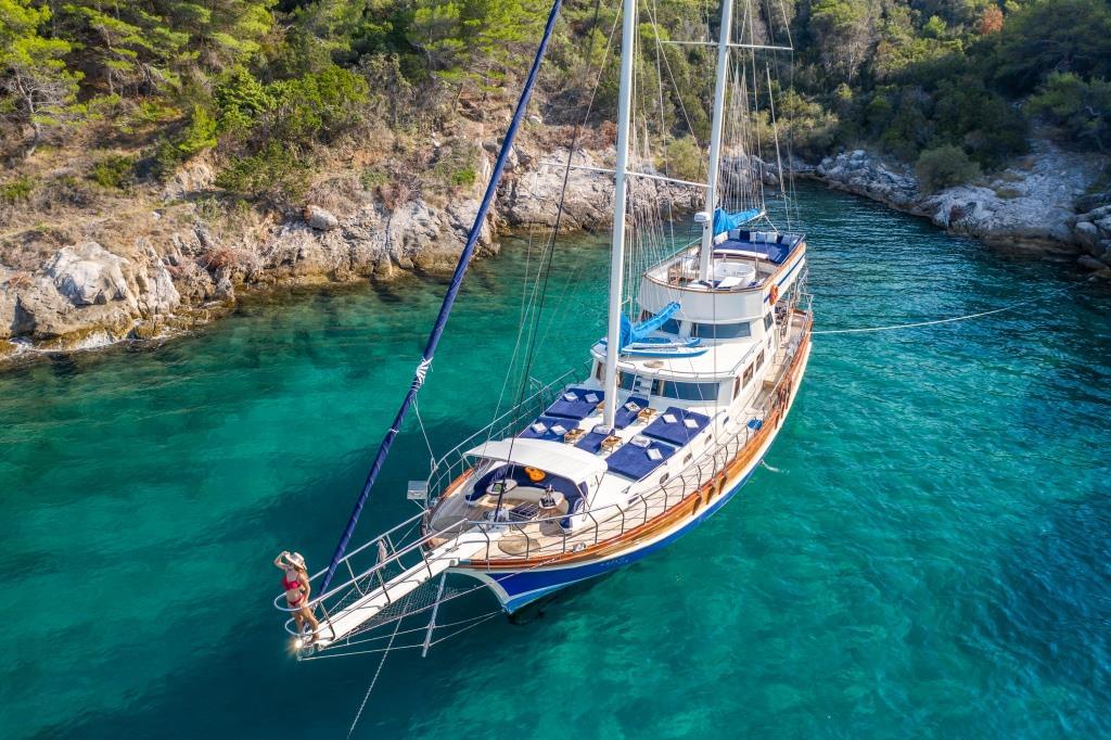 Aerial view luxury wooden gulet yacht anchored pristine turquoise Mediterranean cove