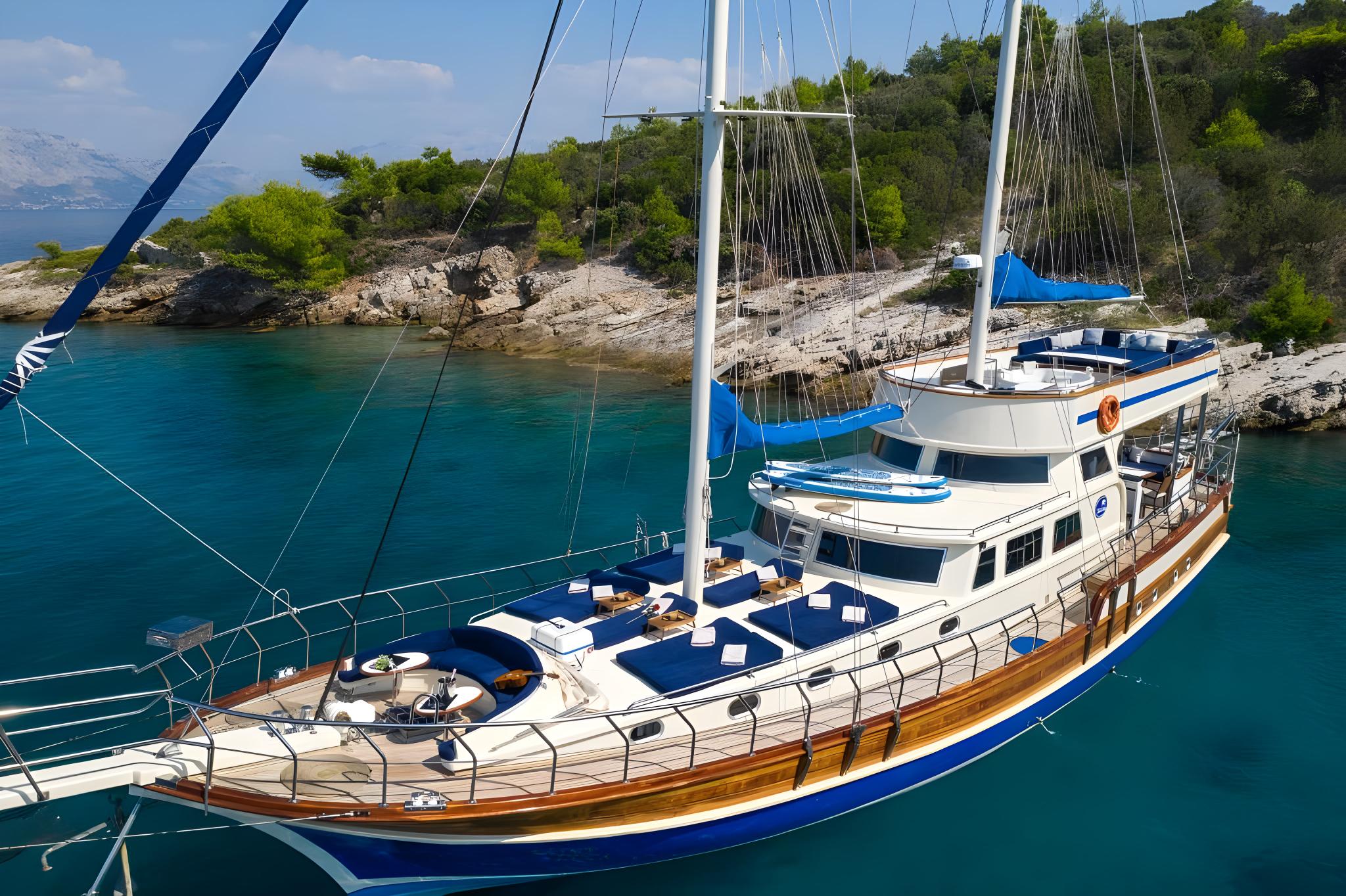 wooden gulet yacht with blue trim anchored in crystal clear turquoise Mediterranean bay