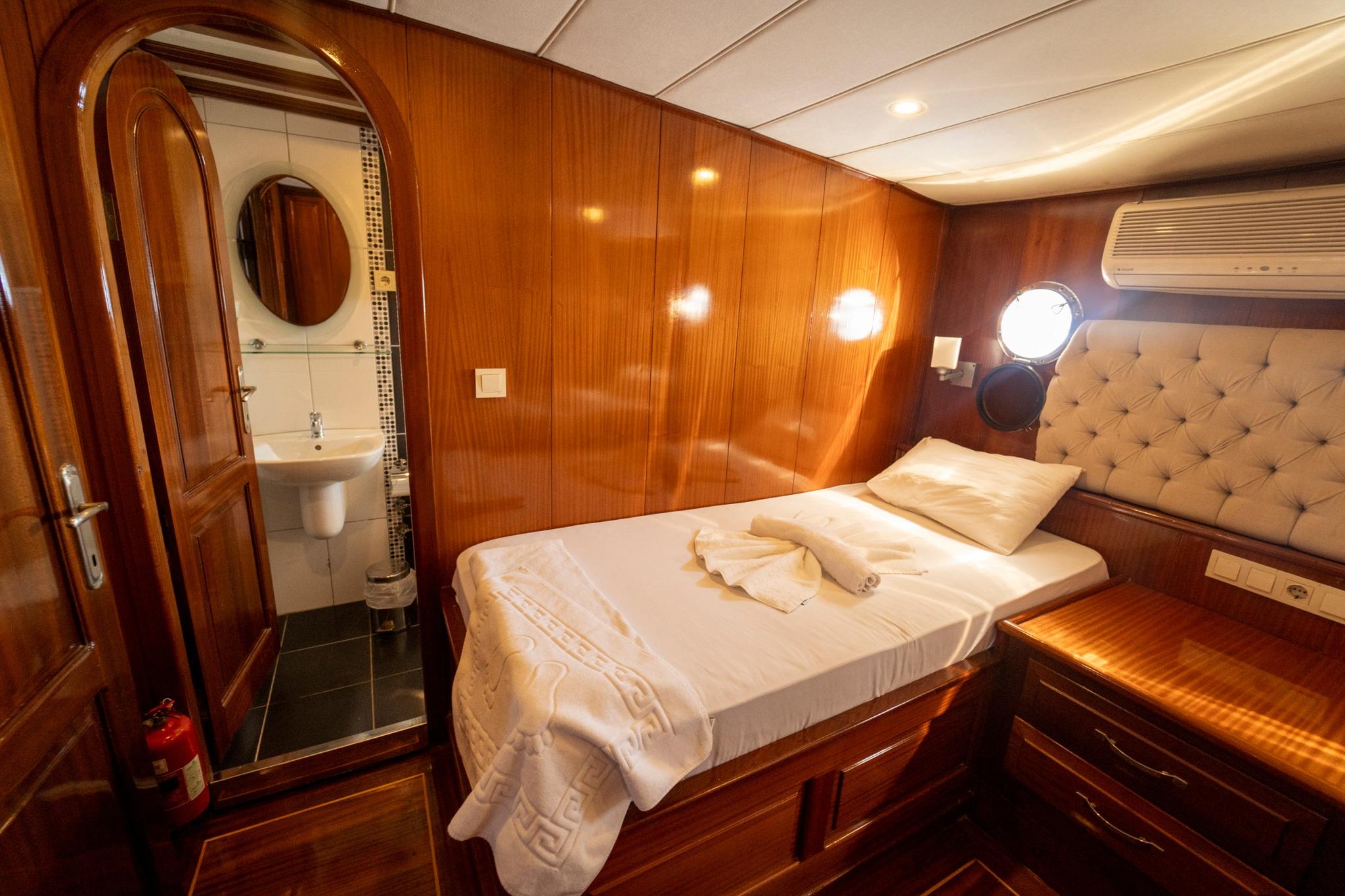 yacht guest cabin featuring double bed with tufted headboard and en-suite bathroom entrance