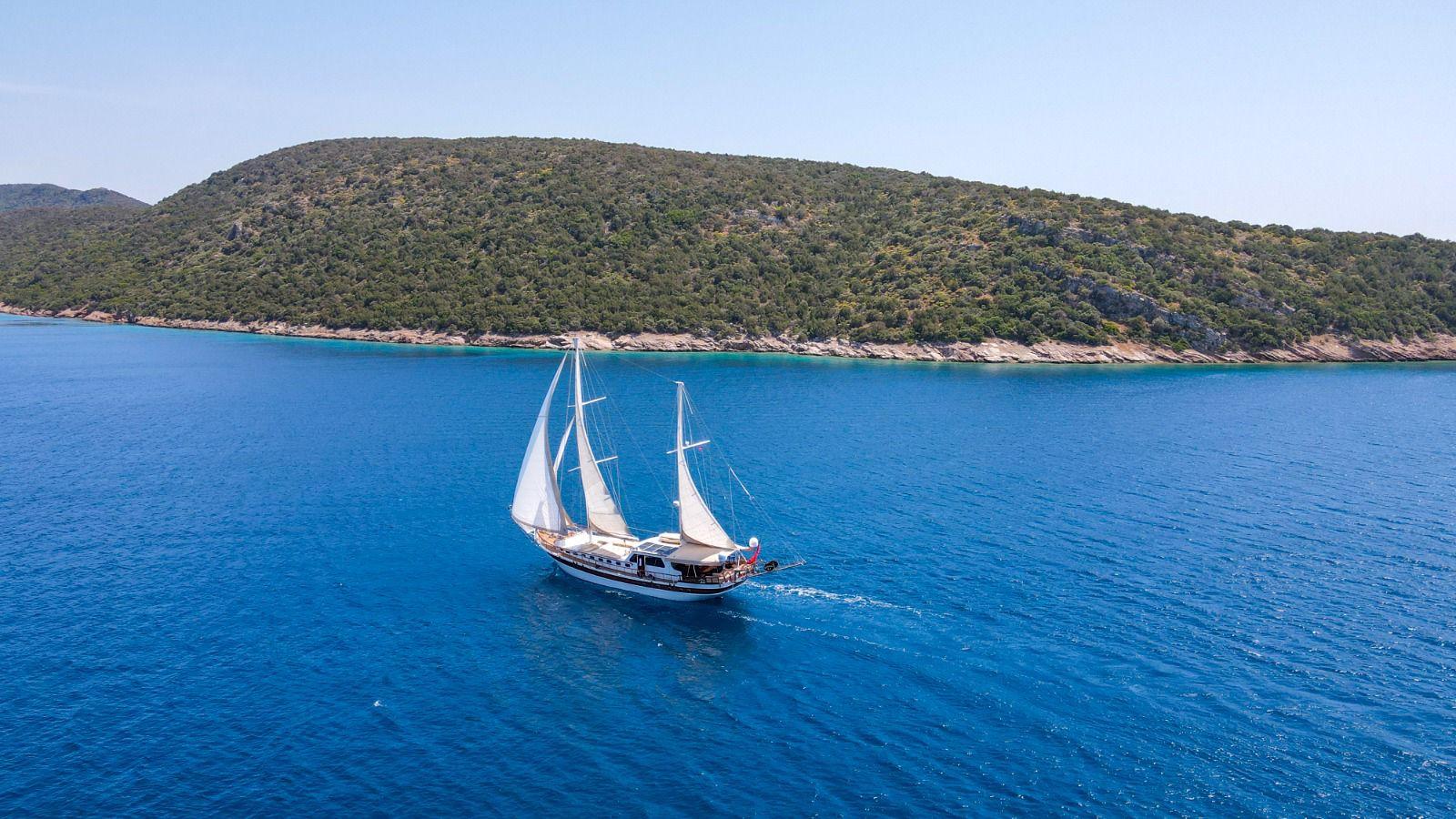aerial view of traditional wooden gulet under sail in crystal blue Mediterranean waters