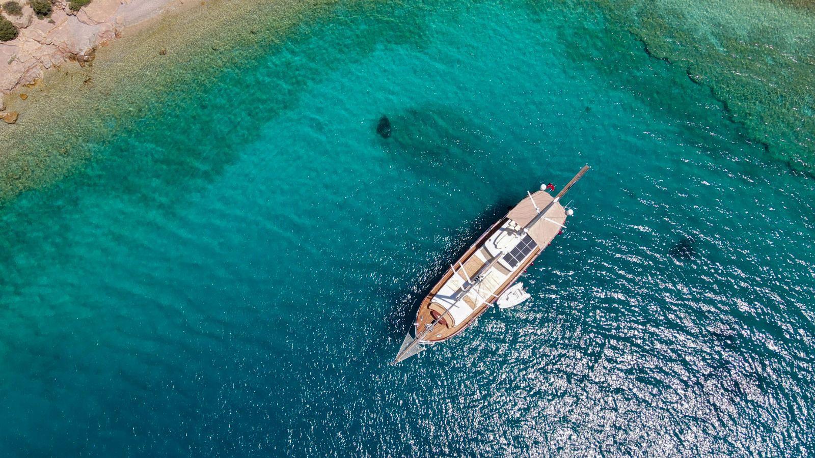 aerial view of traditional wooden gulet yacht at anchor in crystal clear turquoise waters