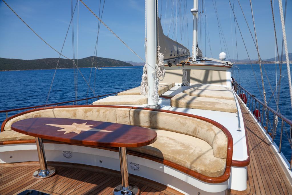 gulet bow deck with curved cream upholstered banquette seating around oval wooden table