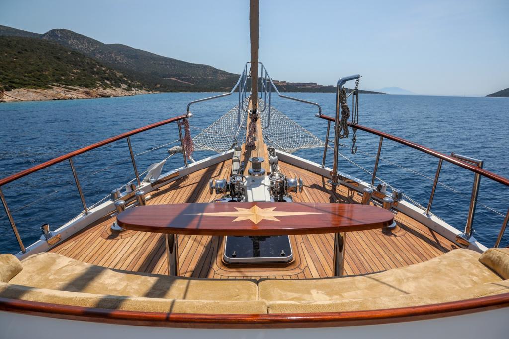 gulet bow deck with polished wood dining table, teak decking and safety railings