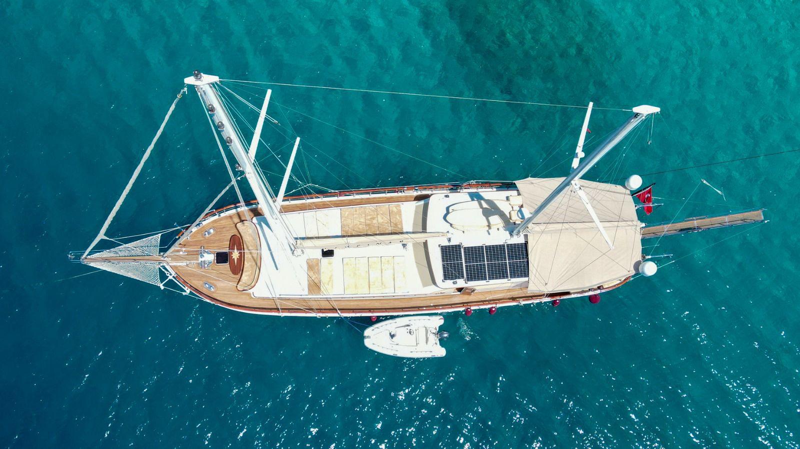 aerial view of traditional wooden gulet yacht with two masts anchored in crystal clear turquoise Mediterranean waters