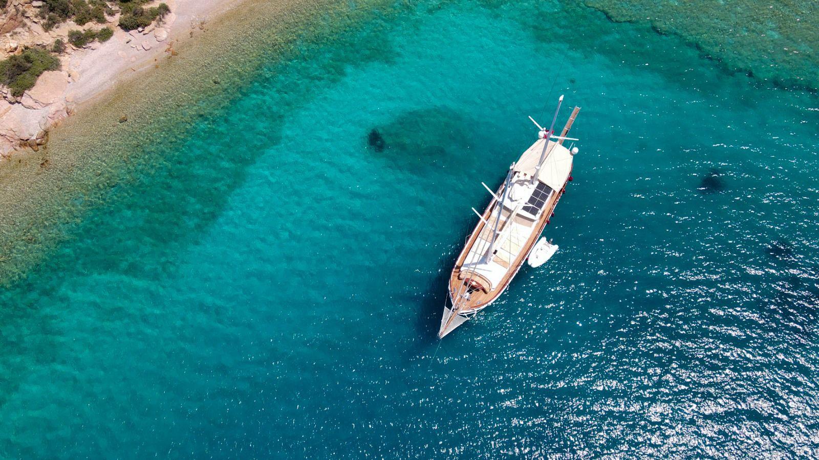 aerial view of traditional wooden gulet yacht anchored in crystal clear turquoise Mediterranean bay