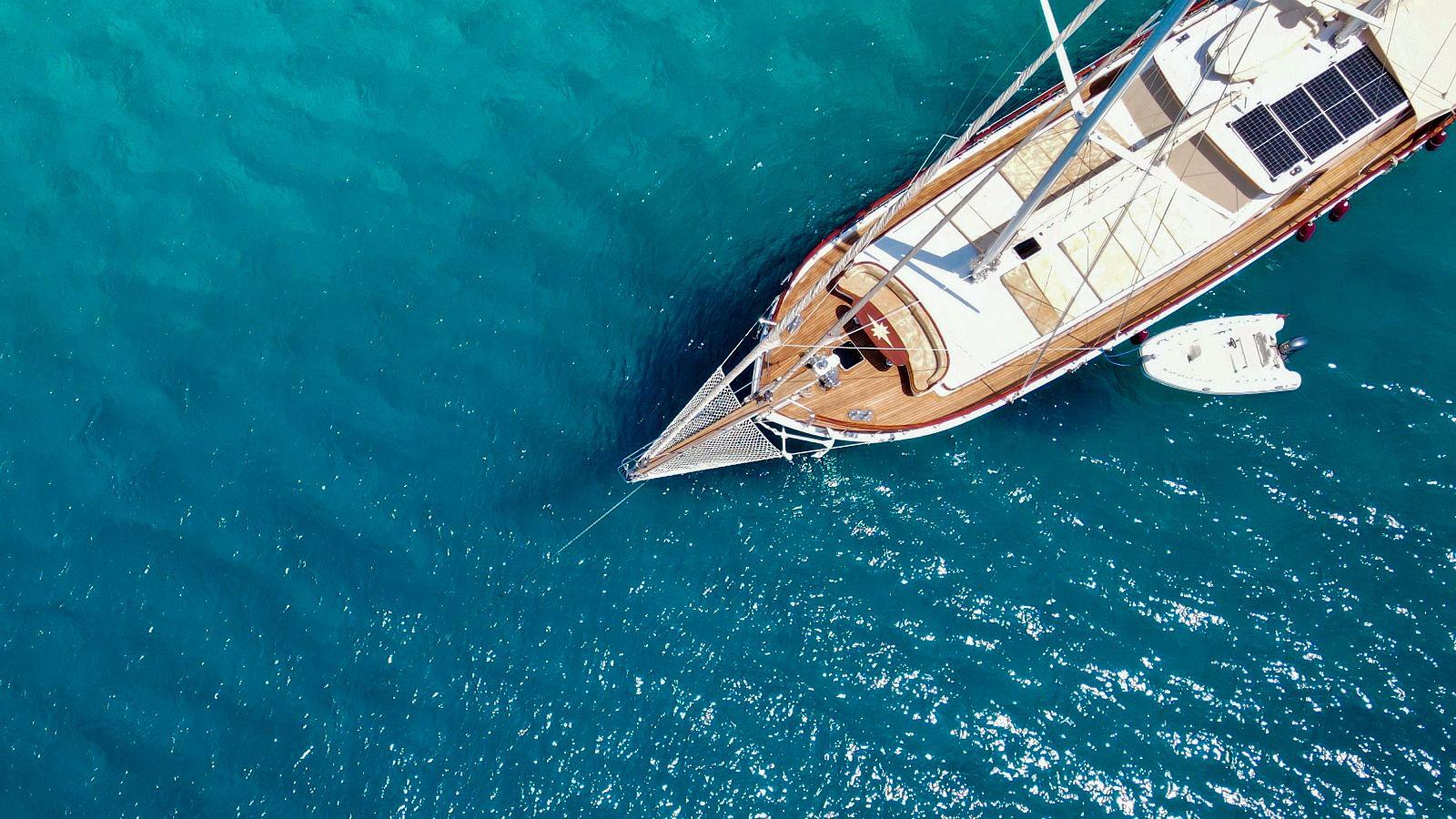 aerial view of traditional gulet yacht with teak decks anchored in crystal clear turquoise Mediterranean waters