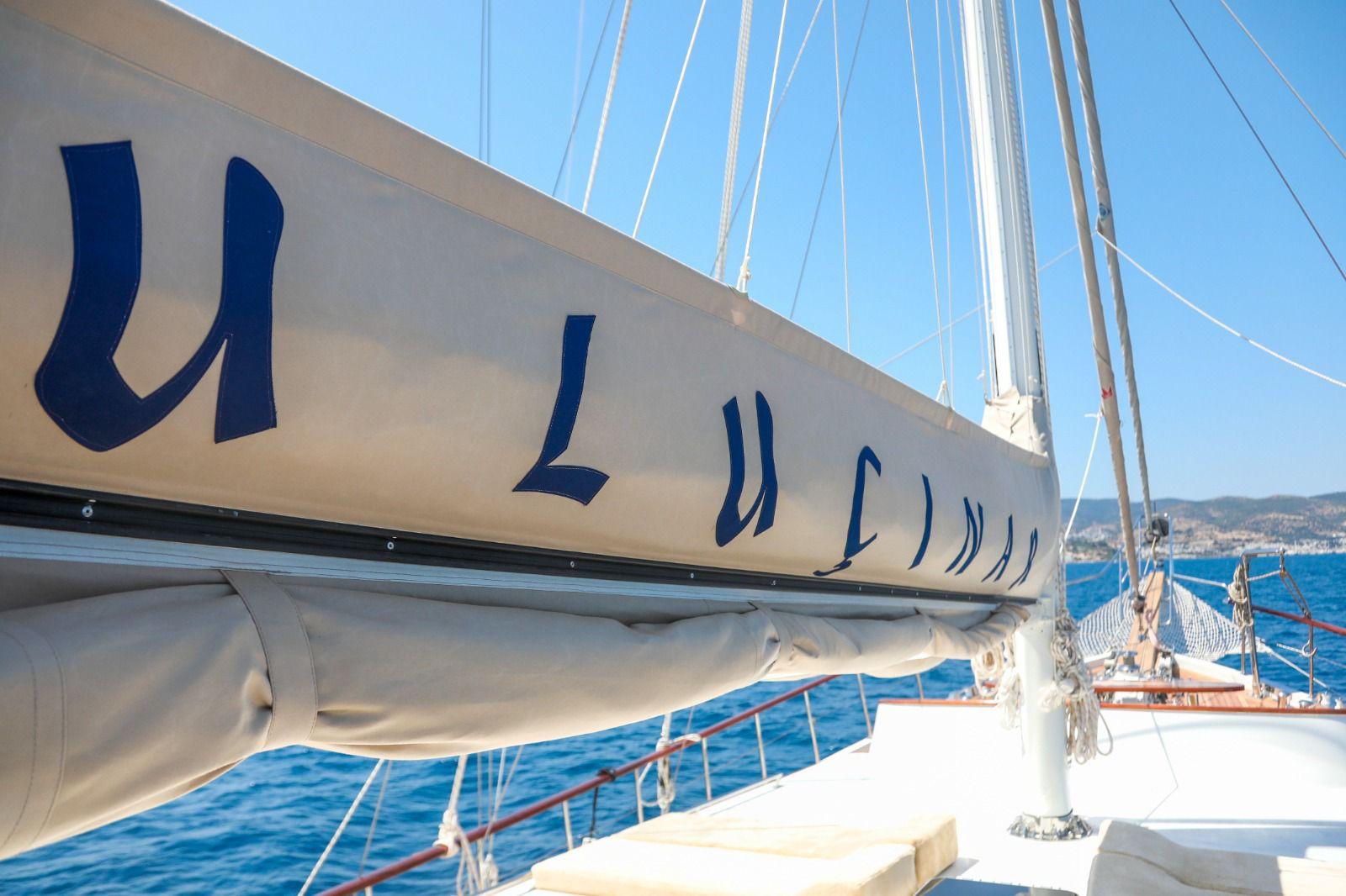 White sailing yacht boom with furled sail and rigging lines against blue Mediterranean waters