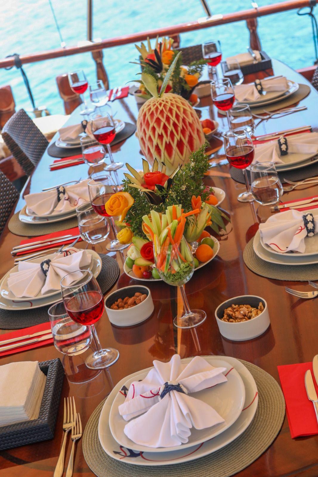yacht dining table with decorative pineapple centerpiece, wine glasses, and formal place settings