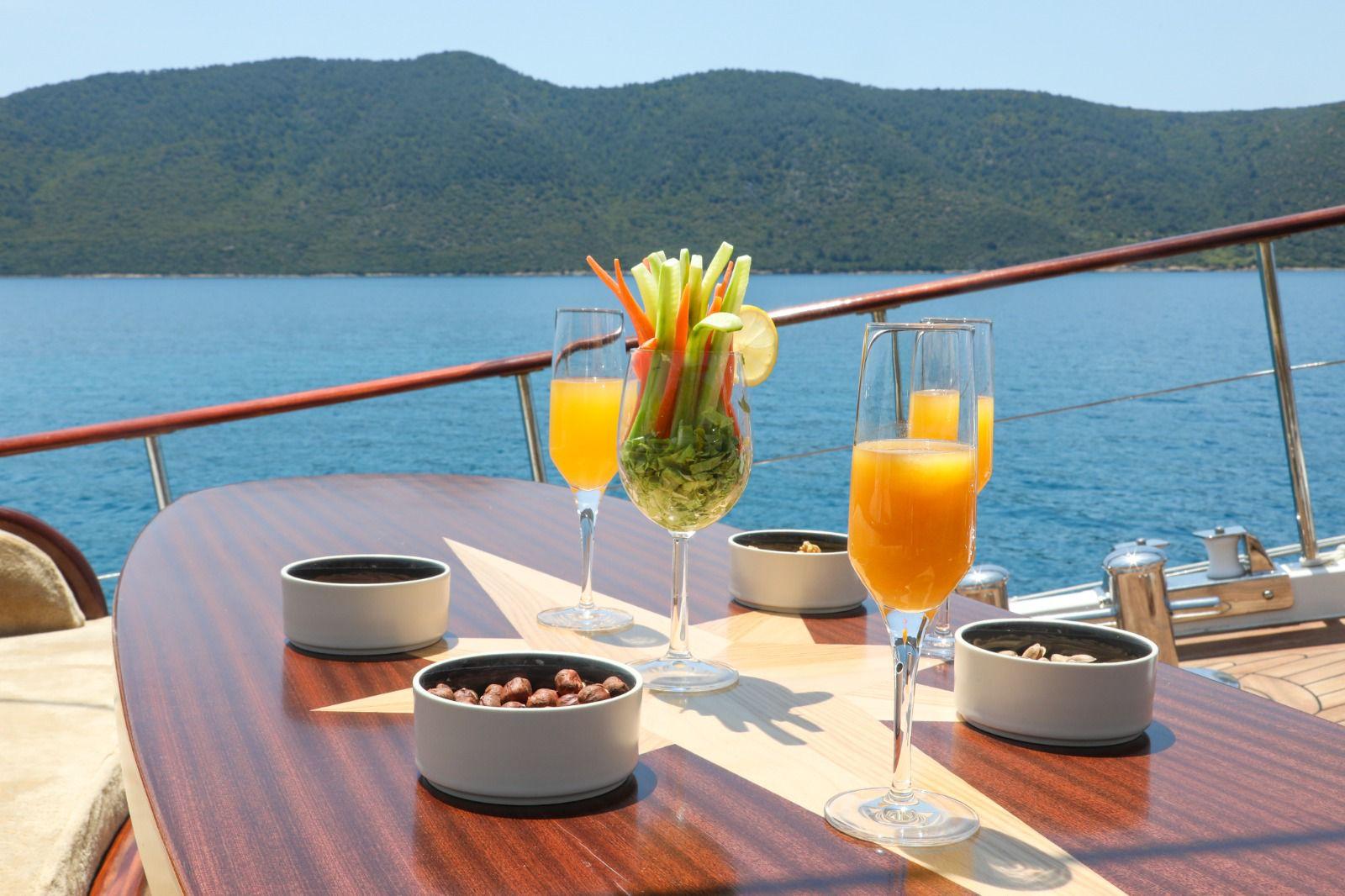 yacht deck dining table with orange juice glasses and appetizer bowls overlooking coastal bay