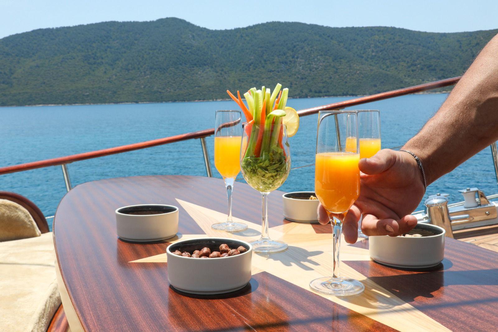 orange juice and vegetable crudité being served at yacht deck dining table