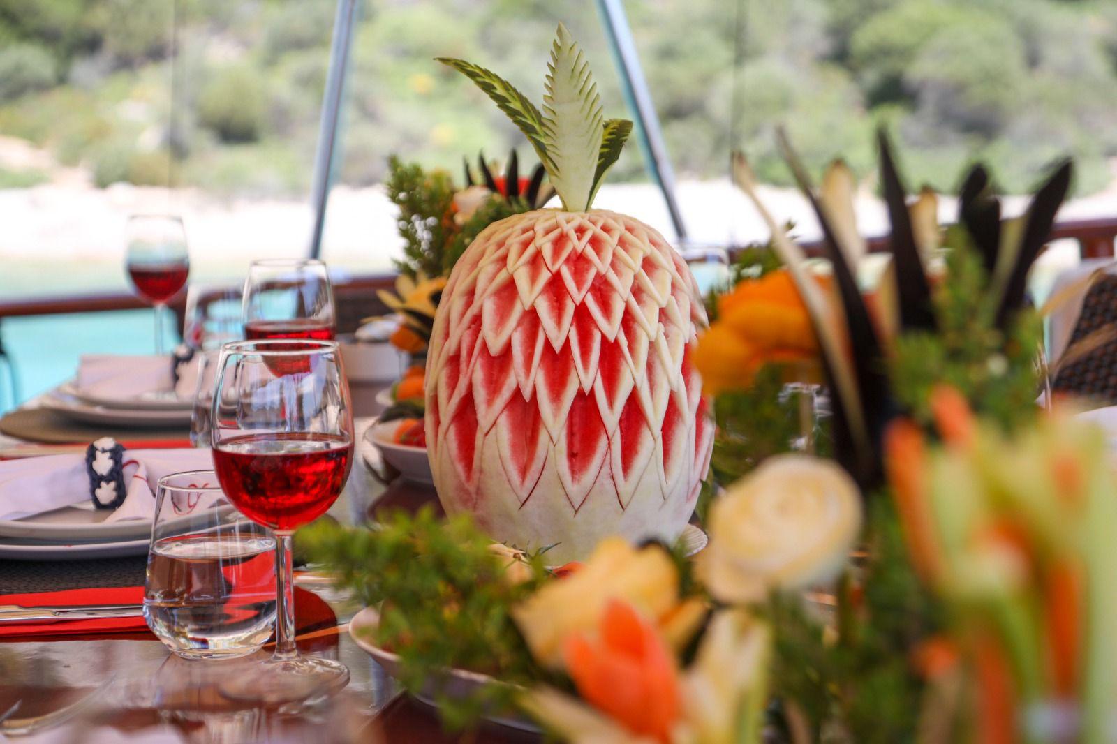 elegant dining table with intricately carved watermelon centerpiece and red wine glasses