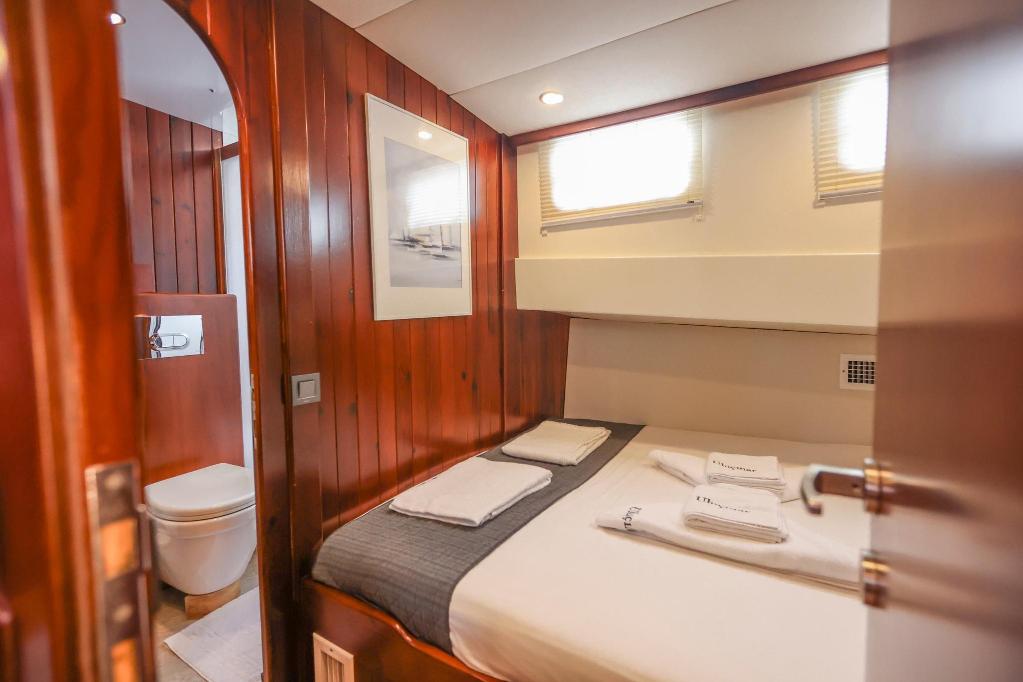 yacht guest cabin featuring double bed with white linens and compact ensuite bathroom