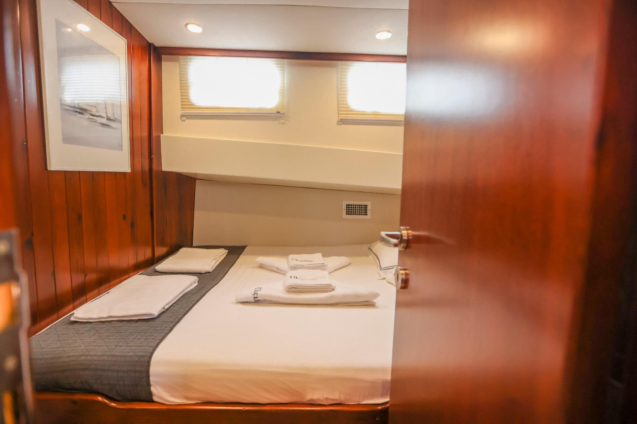 yacht guest cabin featuring double bed with white linens and wooden paneling