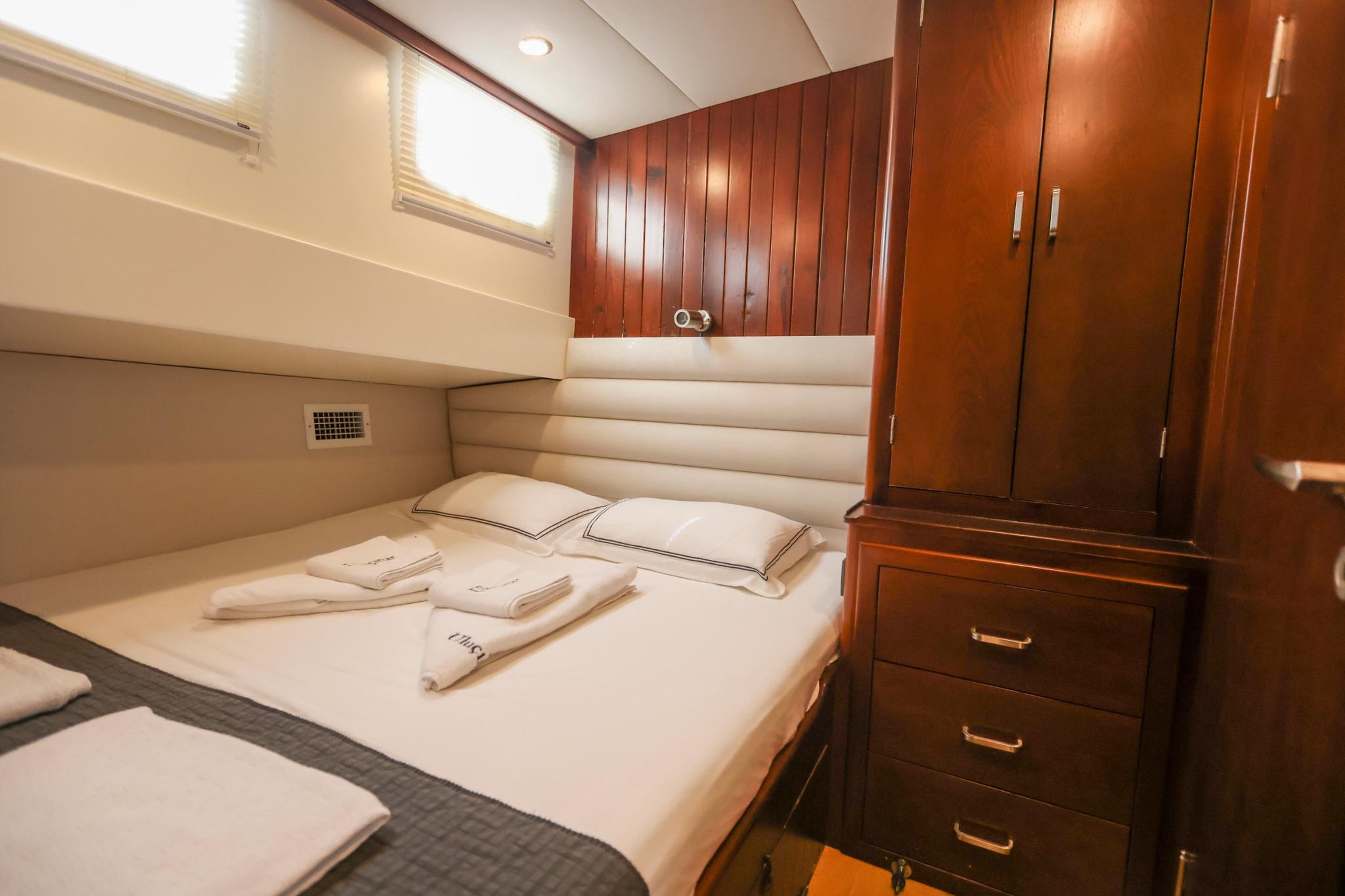 yacht guest cabin featuring double bed with white linens and mahogany wardrobe storage