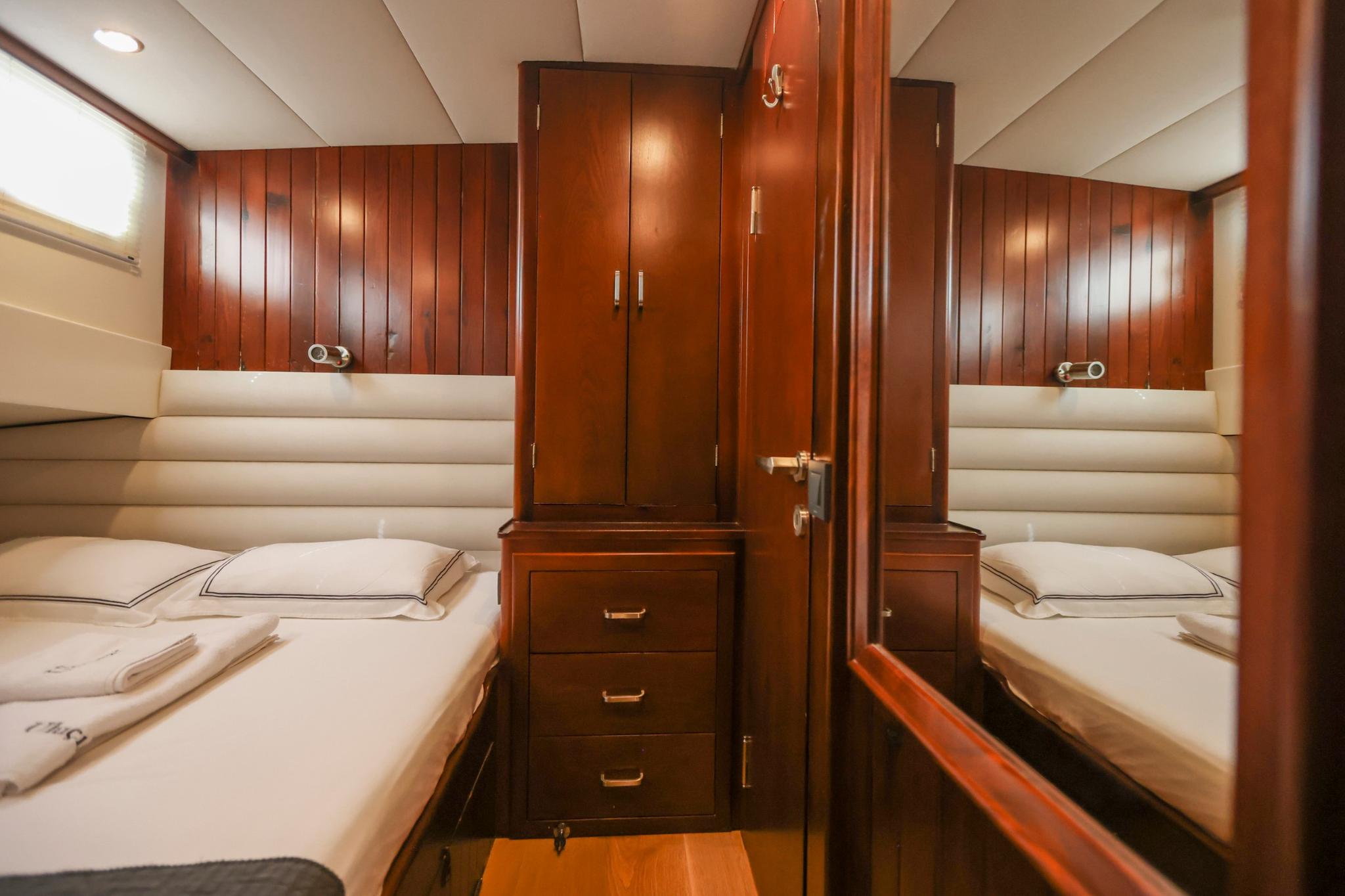 Twin cabin interior with two single beds, central wardrobe unit and cream upholstery