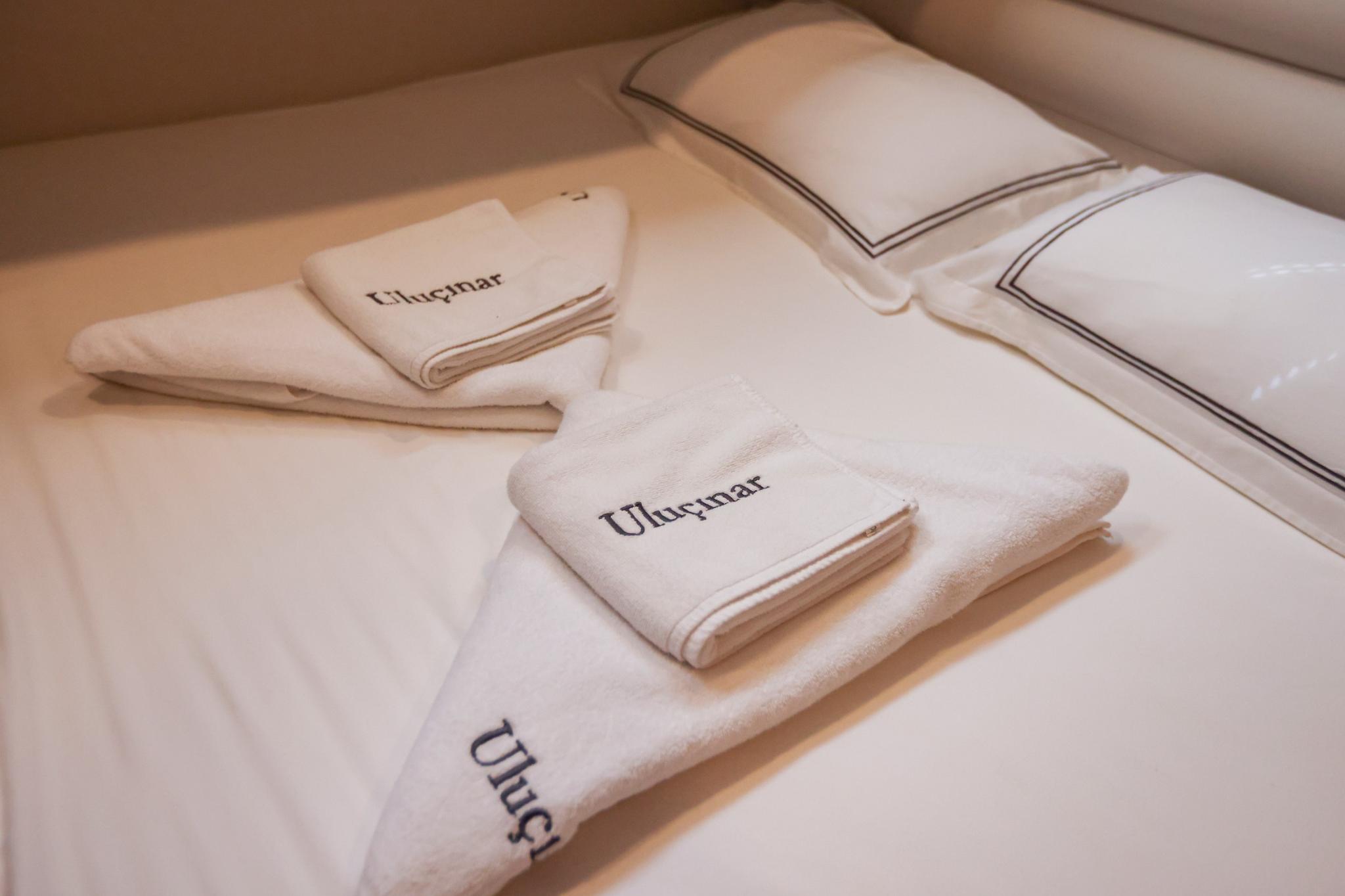 yacht cabin bed with white Ulucnar branded towels and striped pillows