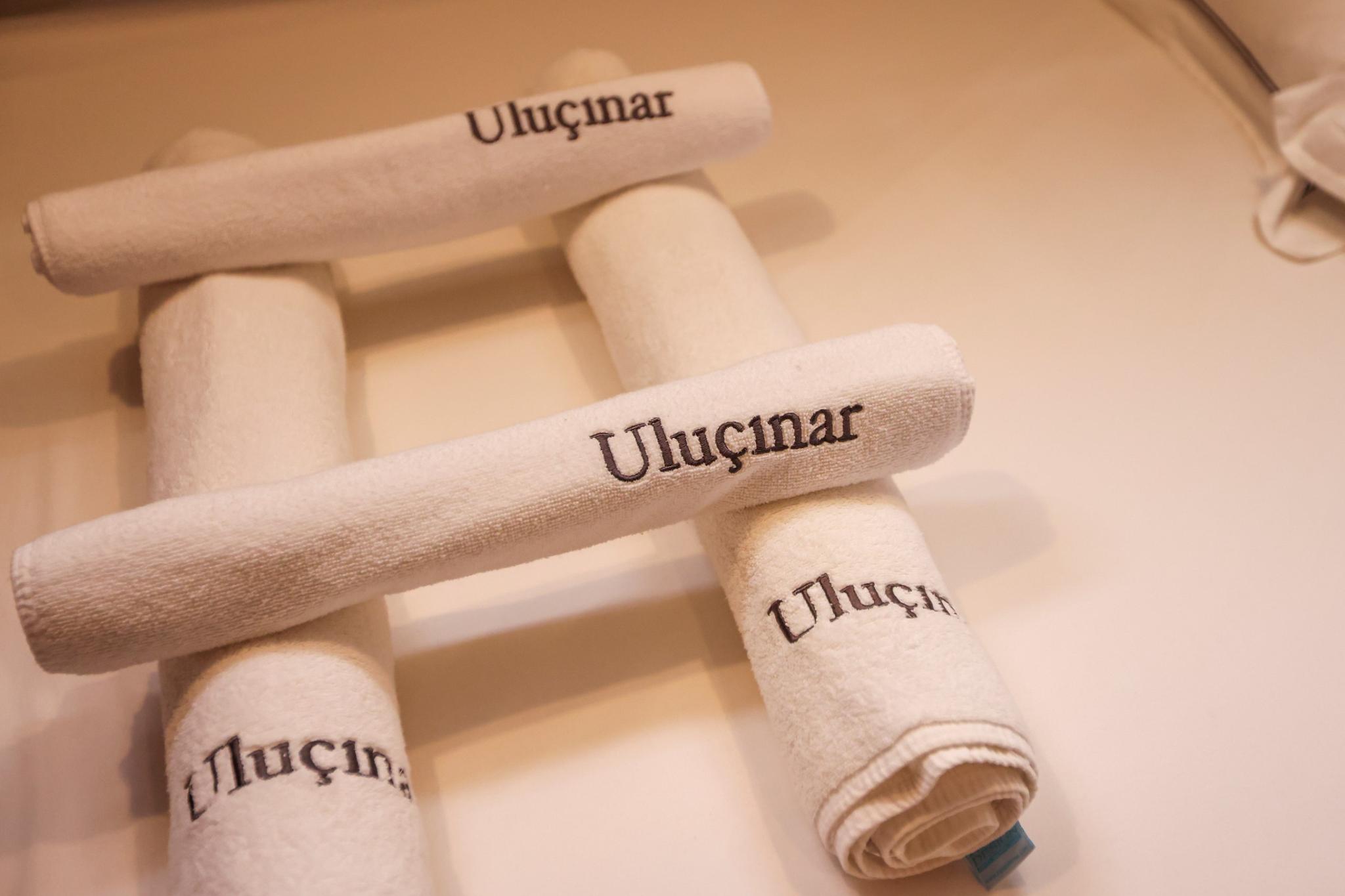 cream colored towels embroidered with Uluçınar yacht name arranged in bathroom