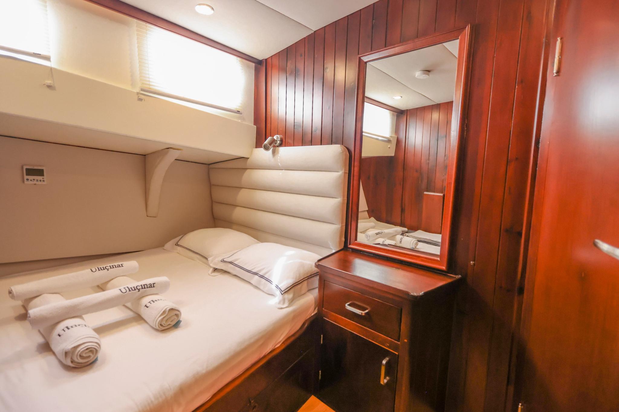 guest cabin featuring double bed with white linens and built-in vanity with mirror