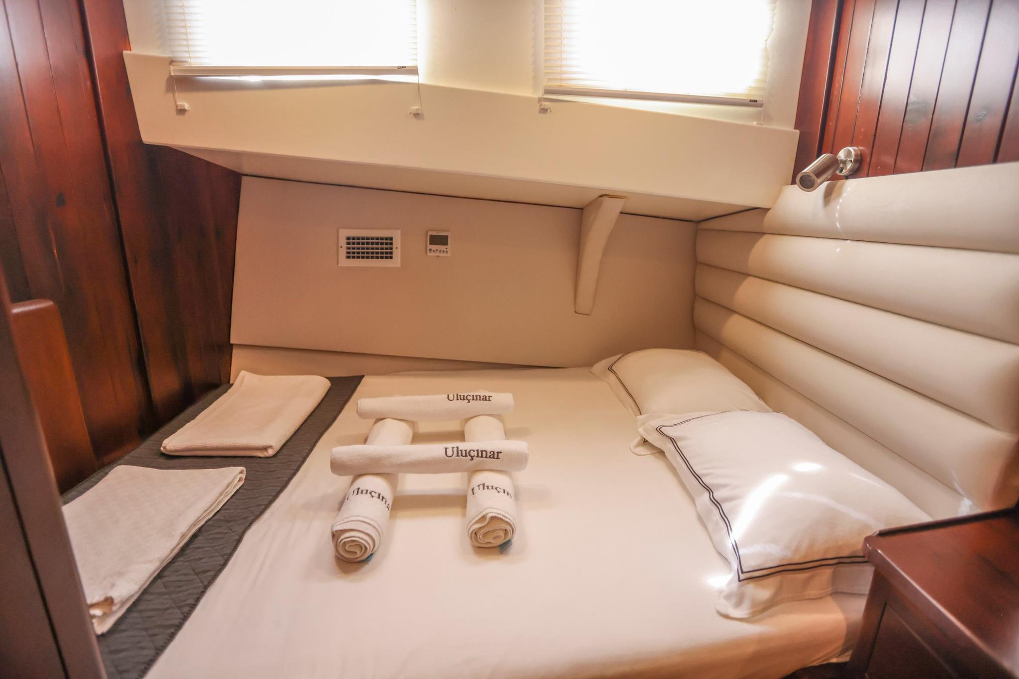 yacht guest cabin with double bed, cream leather seating and branded towels