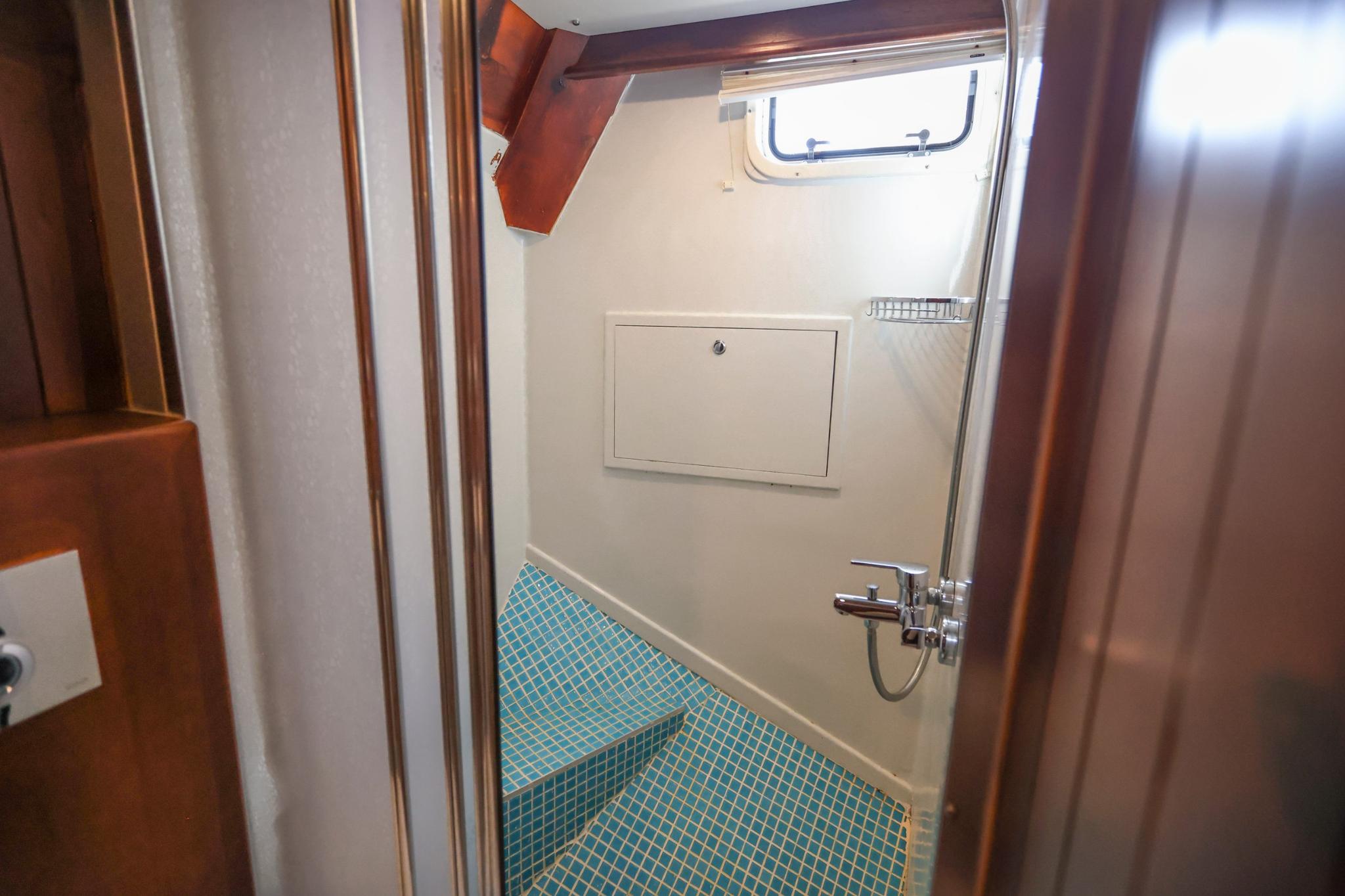 yacht bathroom featuring blue mosaic tile flooring and chrome shower fixtures